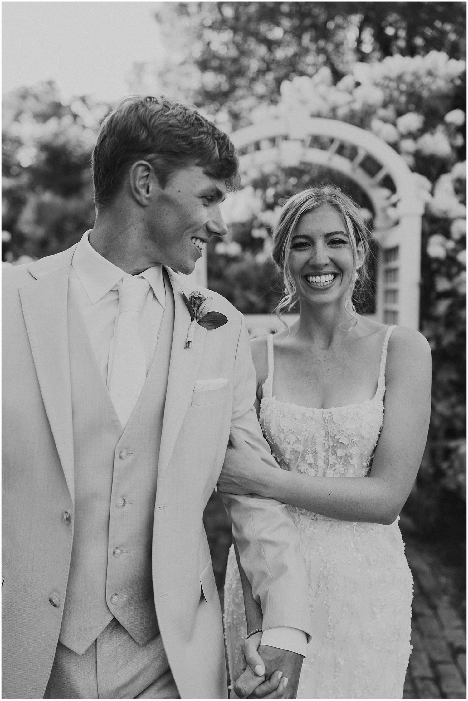 Black and white portrait of a couple sharing a joyful moment on their wedding day.