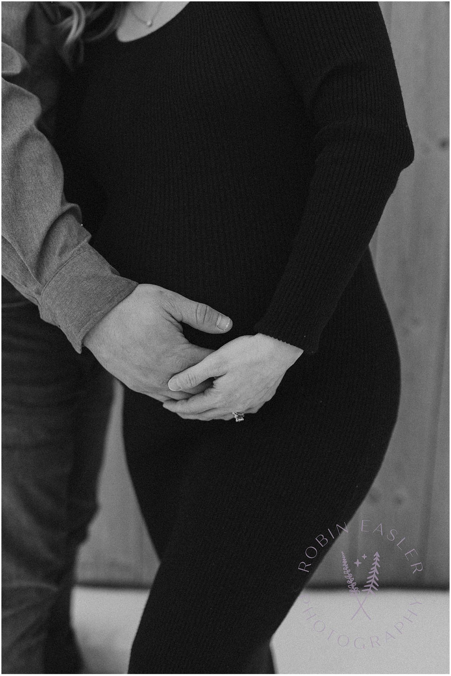 Black and white photo showing hands cradling a pregnant belly.