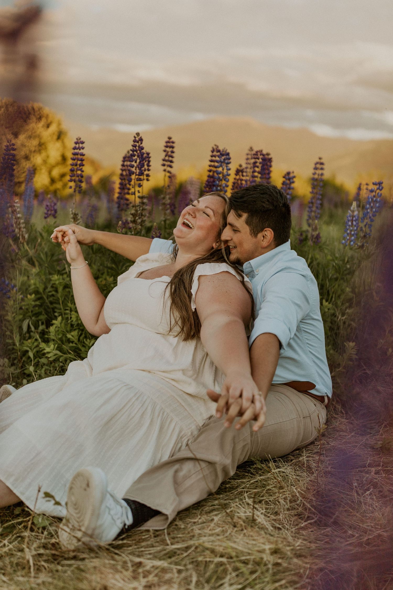 Terise and Jose cuddling up together in a field of purple lupines in Sugar Hill New Hampshire.