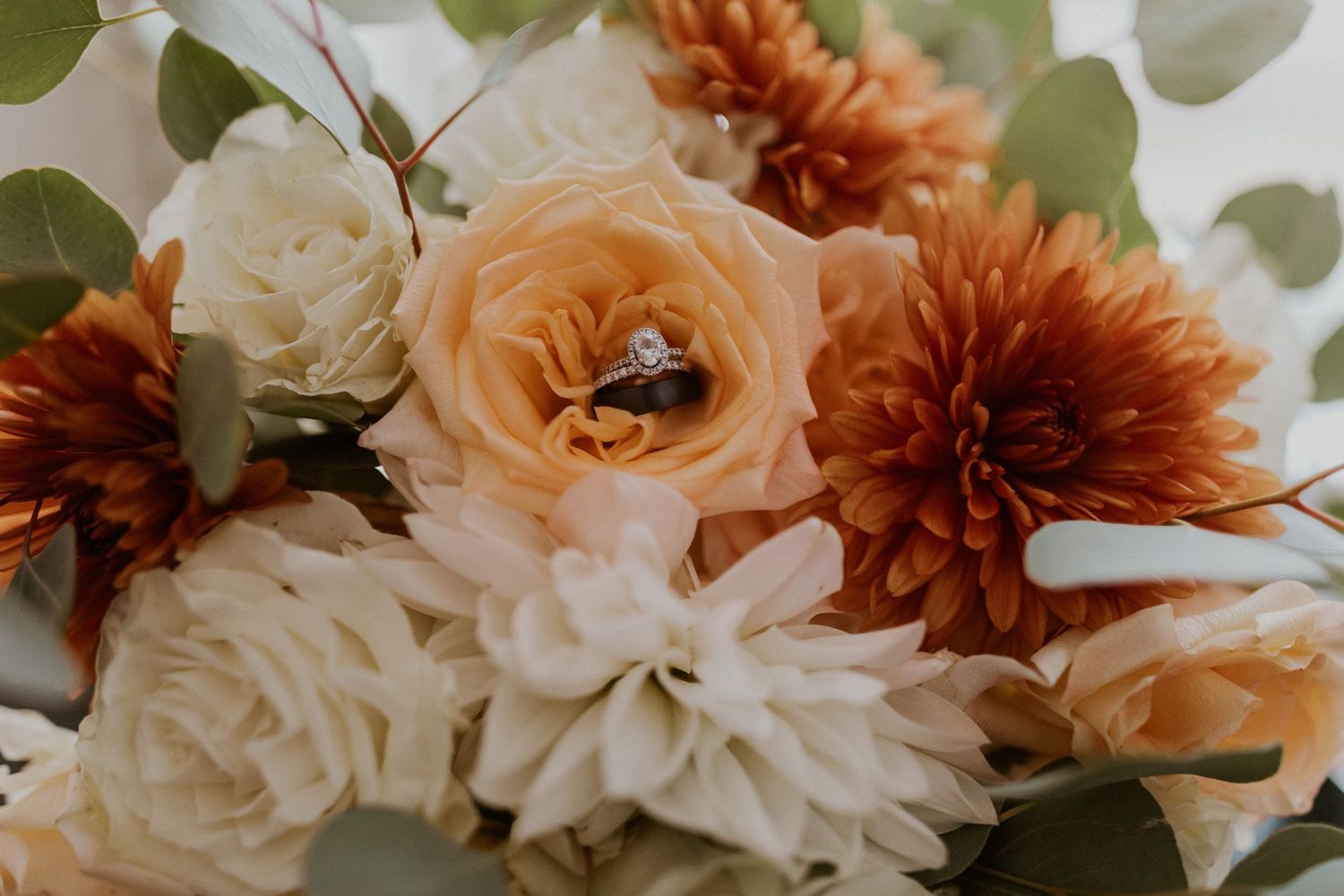 A detail photograph of the wedding rings placed on the bride's bouquet.