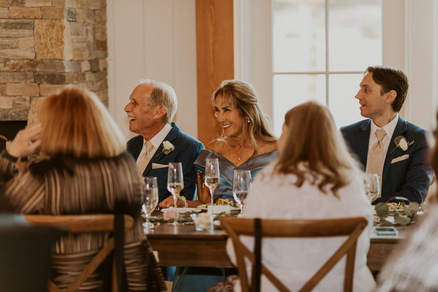 A candid photograph of the grooms mother reacting to toasts during the reception in the Lake House at Owls Nest Resort.