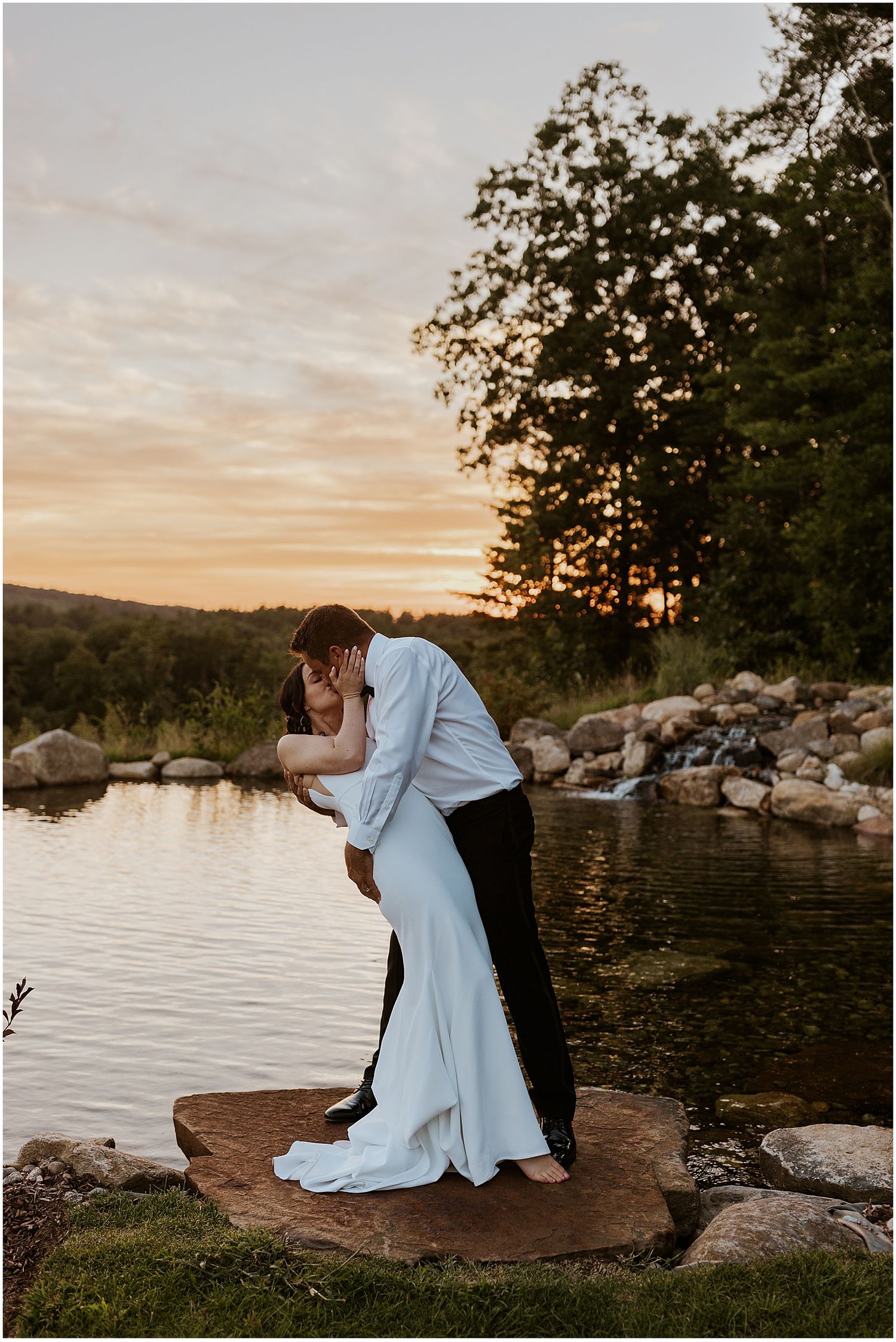 Romantic sunset portrait session by a lakeside with rocky shoreline.
