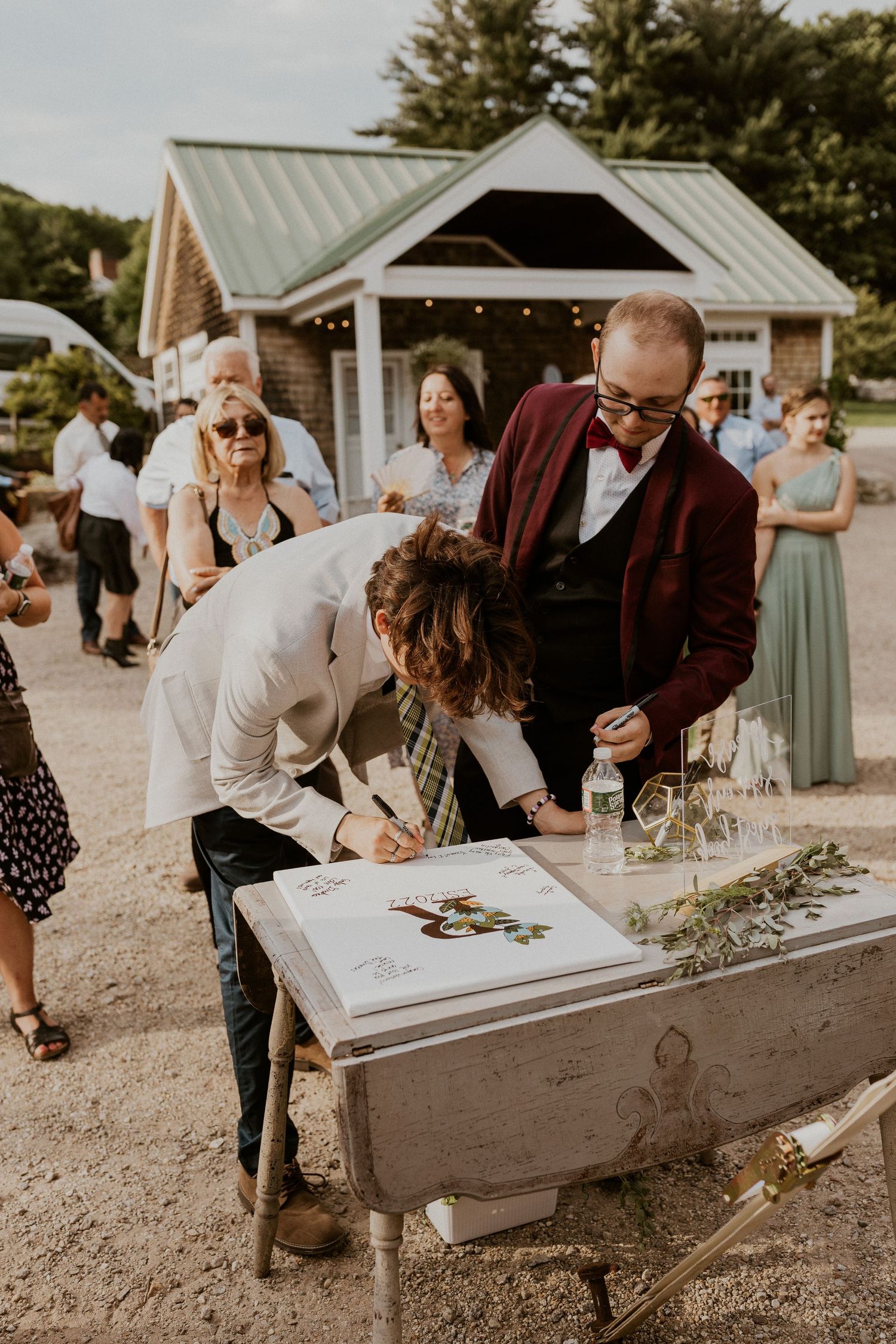 Wedding guests signing a creative guest book display made from a vintage wheelbarrow.