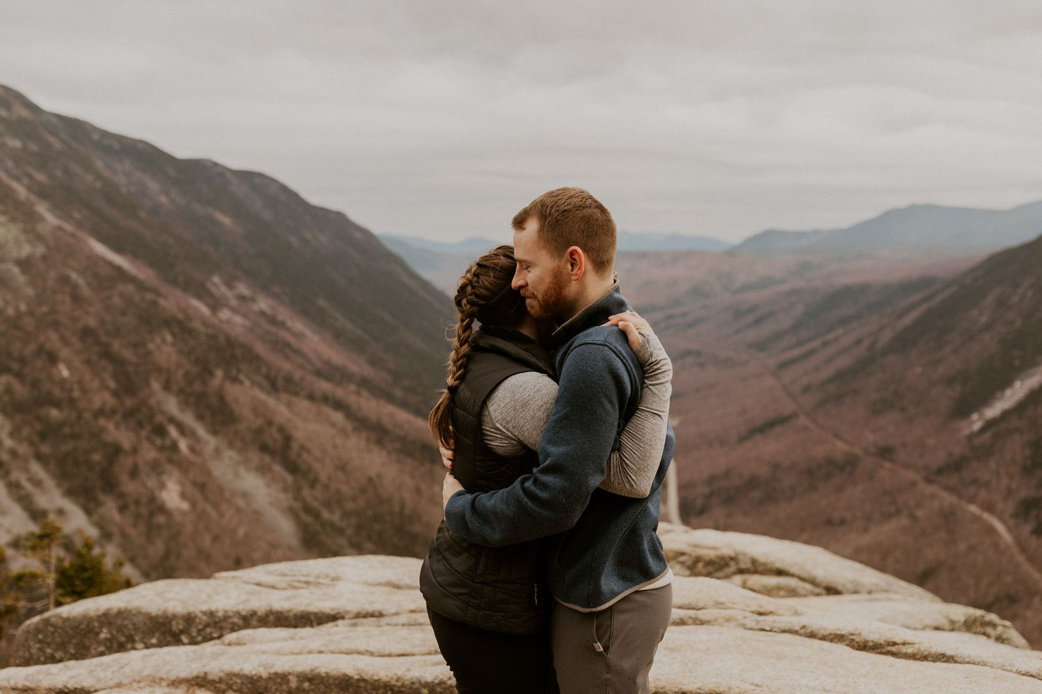 Newly engaged couple embracing each other on top of Mount Willard in the White Mountains of New Hampshire.