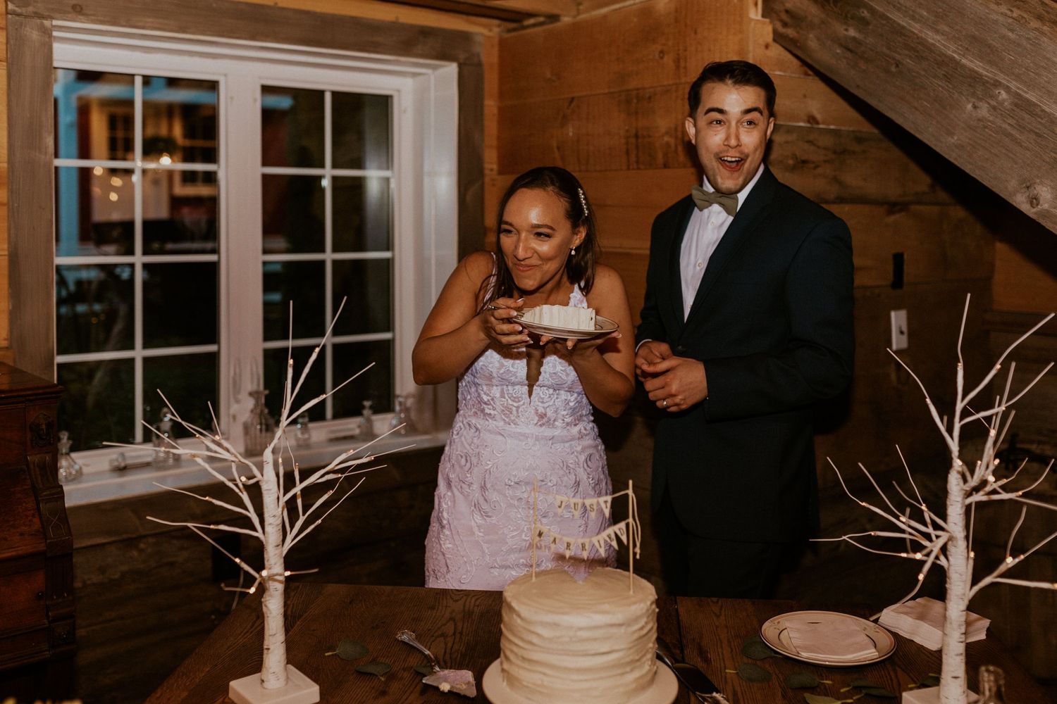 Wedding couple engaging in playful cake feeding moment during reception.