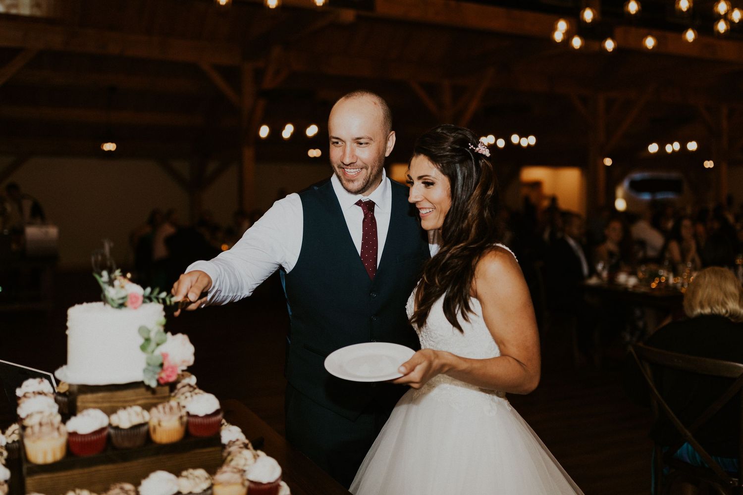 Newlyweds cutting their elegant white wedding cake together at the reception.