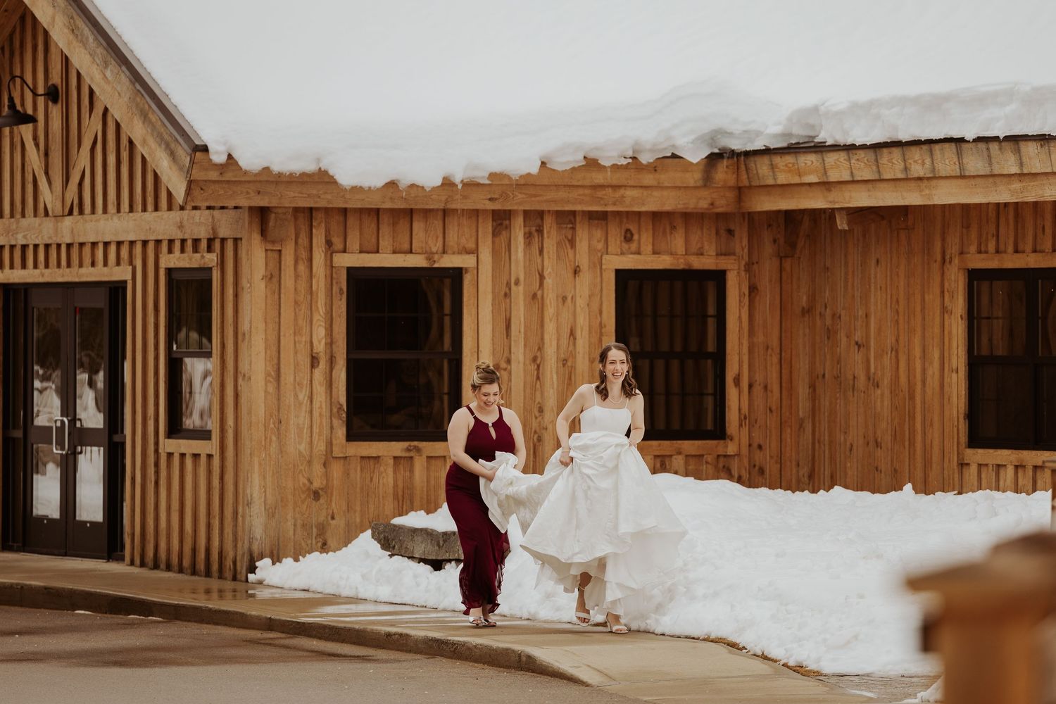 A rustic wooden barn venue decorated for a wedding celebration with people in formal attire seated on benches.