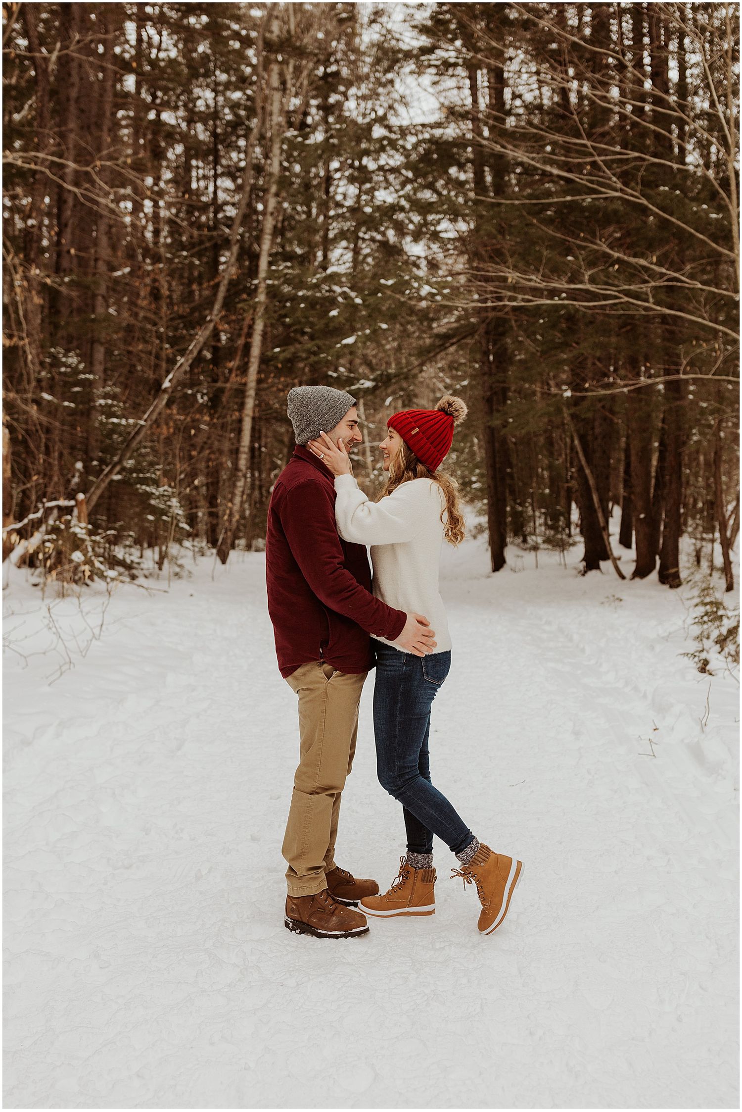 Couple taking engagement pictures in the snow in NH wearing winter engagement photo outfits