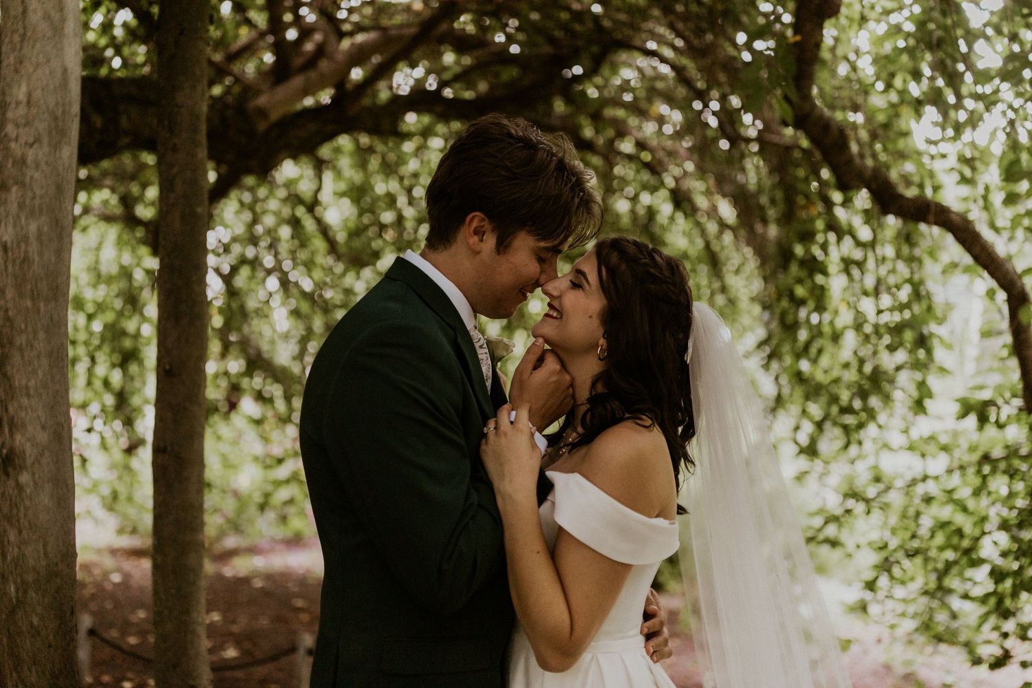 Intimate wedding portrait moment in a sunlit garden setting.