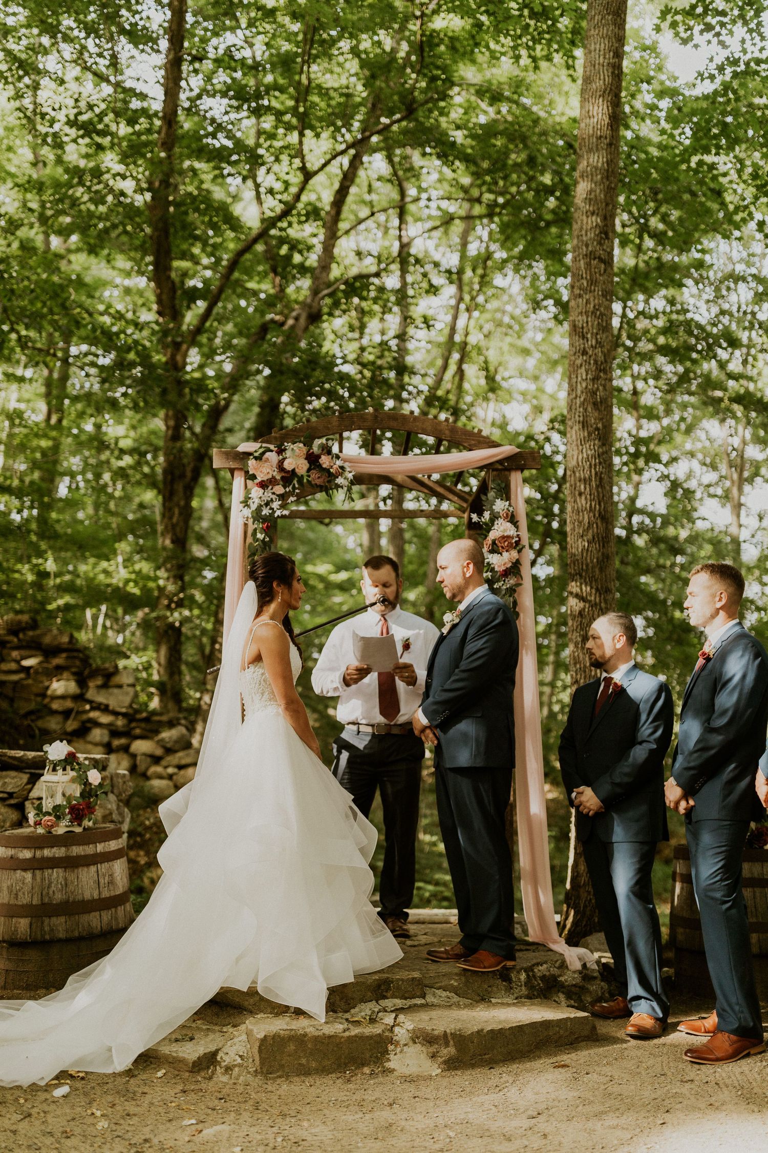 Woodland wedding ceremony with elegant white decor and natural forest backdrop.