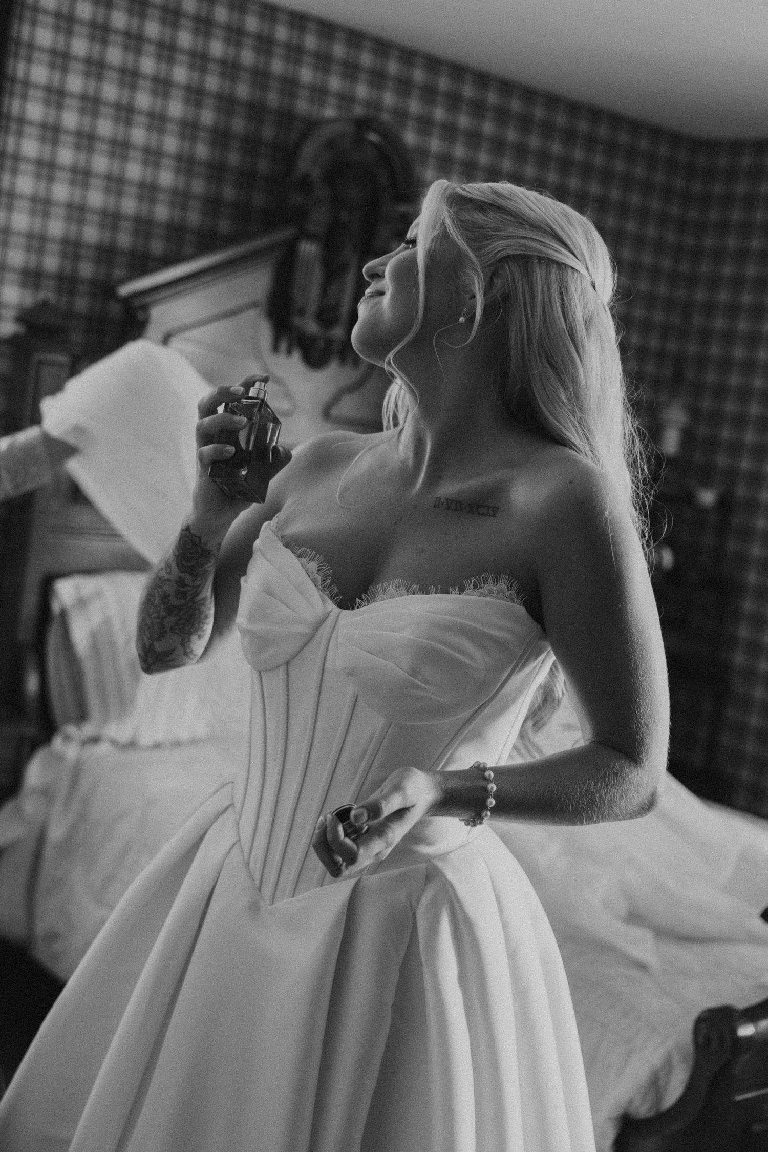 Bride in strapless corset wedding gown applying perfume in black and white bridal preparation photo.