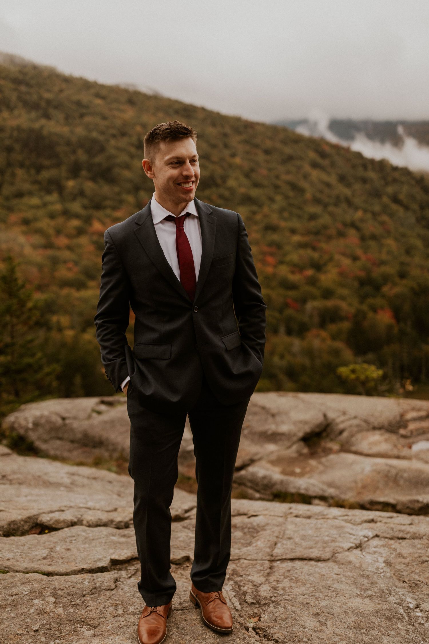 The groom standing by himself for a portrait on the mountain in the White Mountains of New Hampshire.