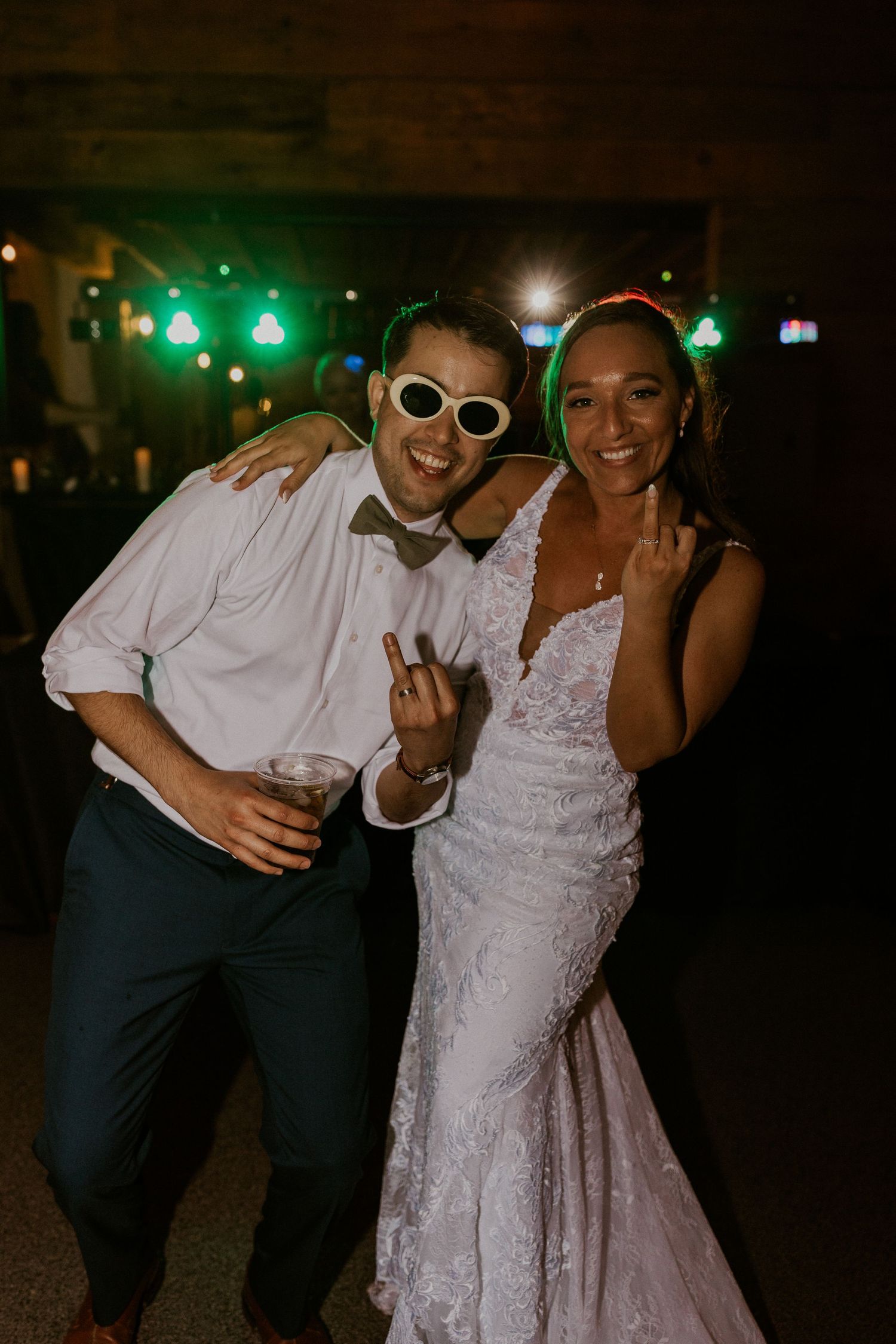 Chrissy and Mike flipping their ring fingers and smiling at the camera while on the dance floor.
