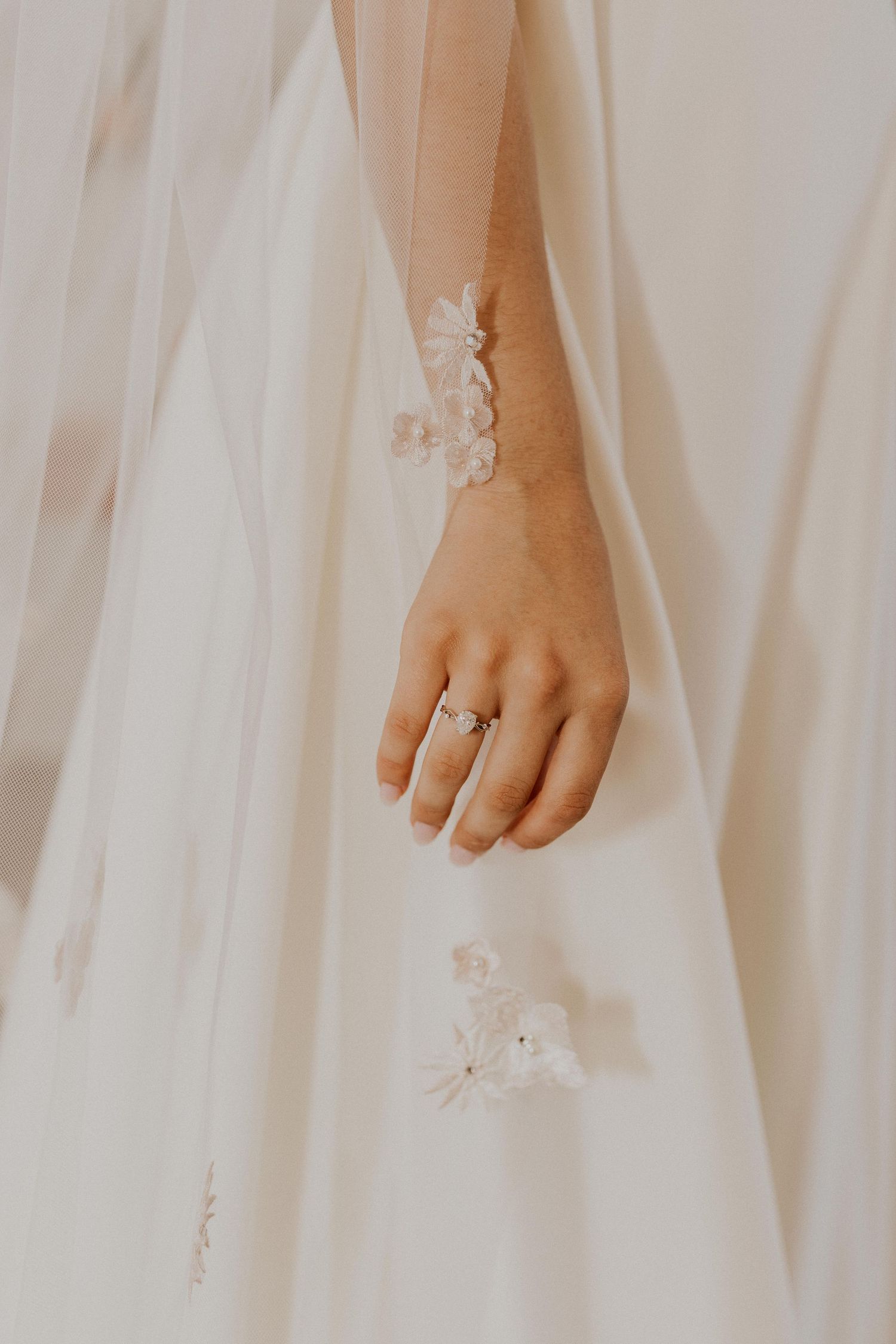 Close-up details of a white wedding dress with delicate lace appliques.