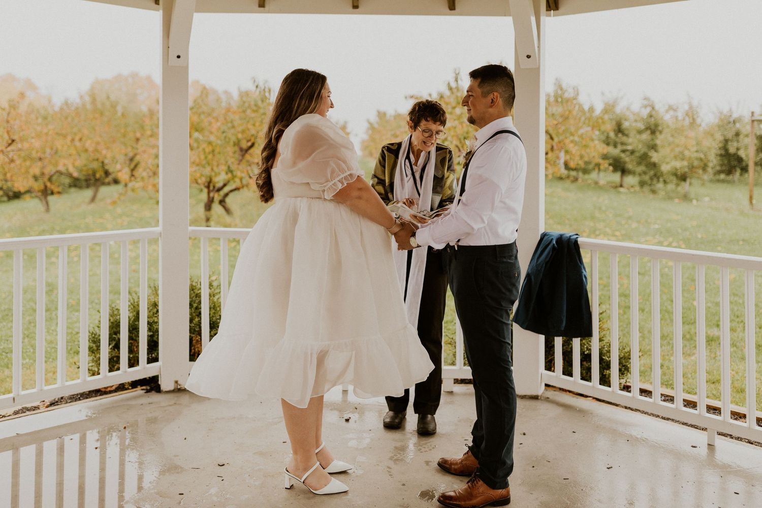Terise and Jose holding hands during their ceremony at Carter Hill Orchard in Concord New Hampshire.