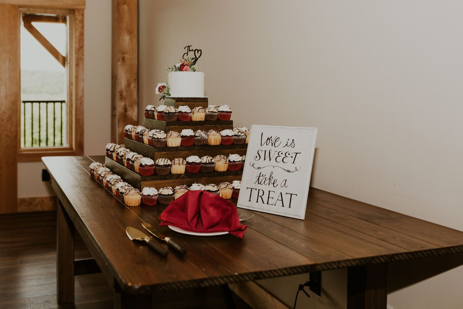 Wedding dessert table with cupcakes and treats displayed on wooden surfaces.