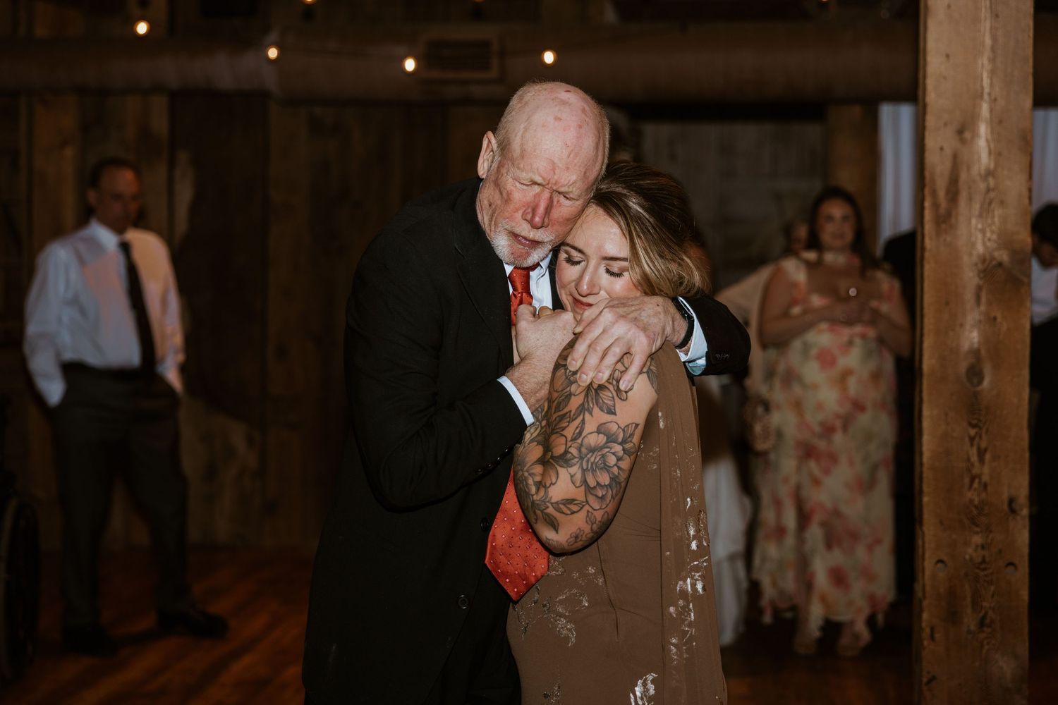 Wedding guests dance and celebrate during an evening reception in a rustic venue.