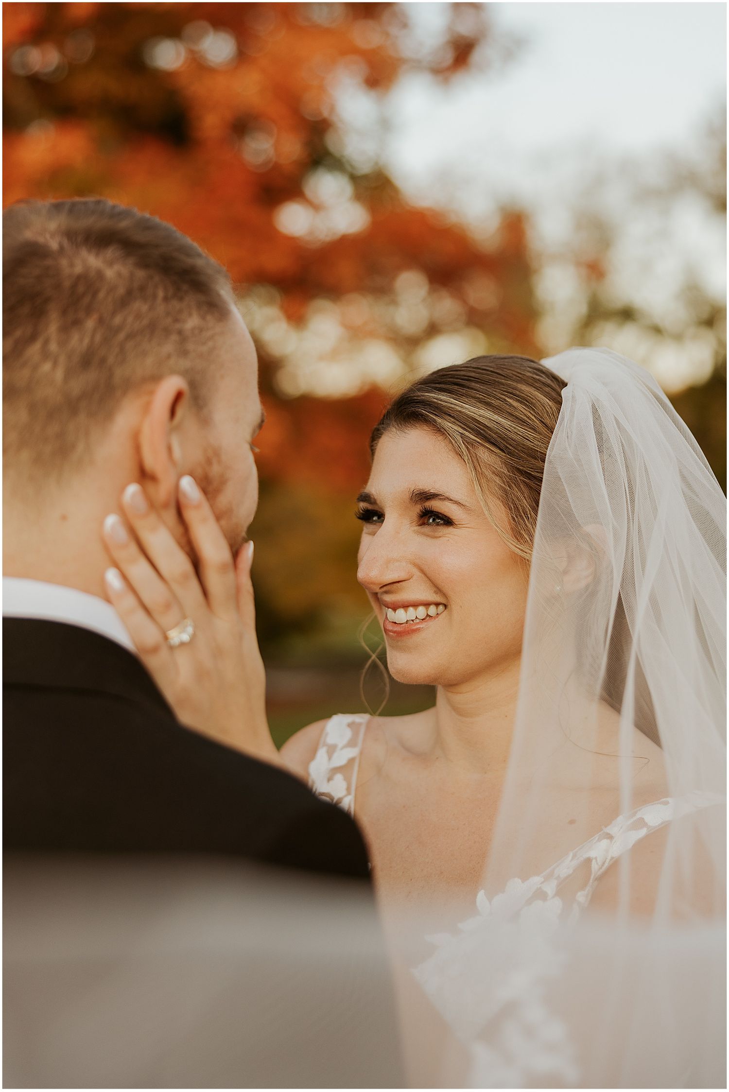 Romantic autumn wedding portraits with warm orange foliage in the background.