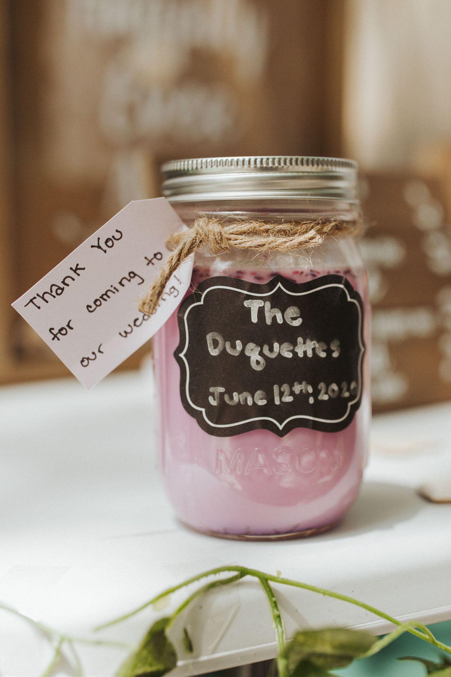 Mason jars with pink contents and chalkboard labels arranged on a white surface.