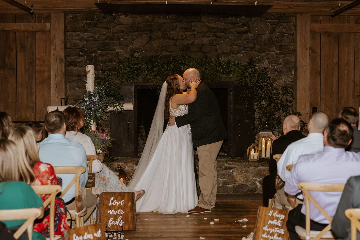 A wedding ceremony in a rustic barn venue with stone backdrop and wooden details.