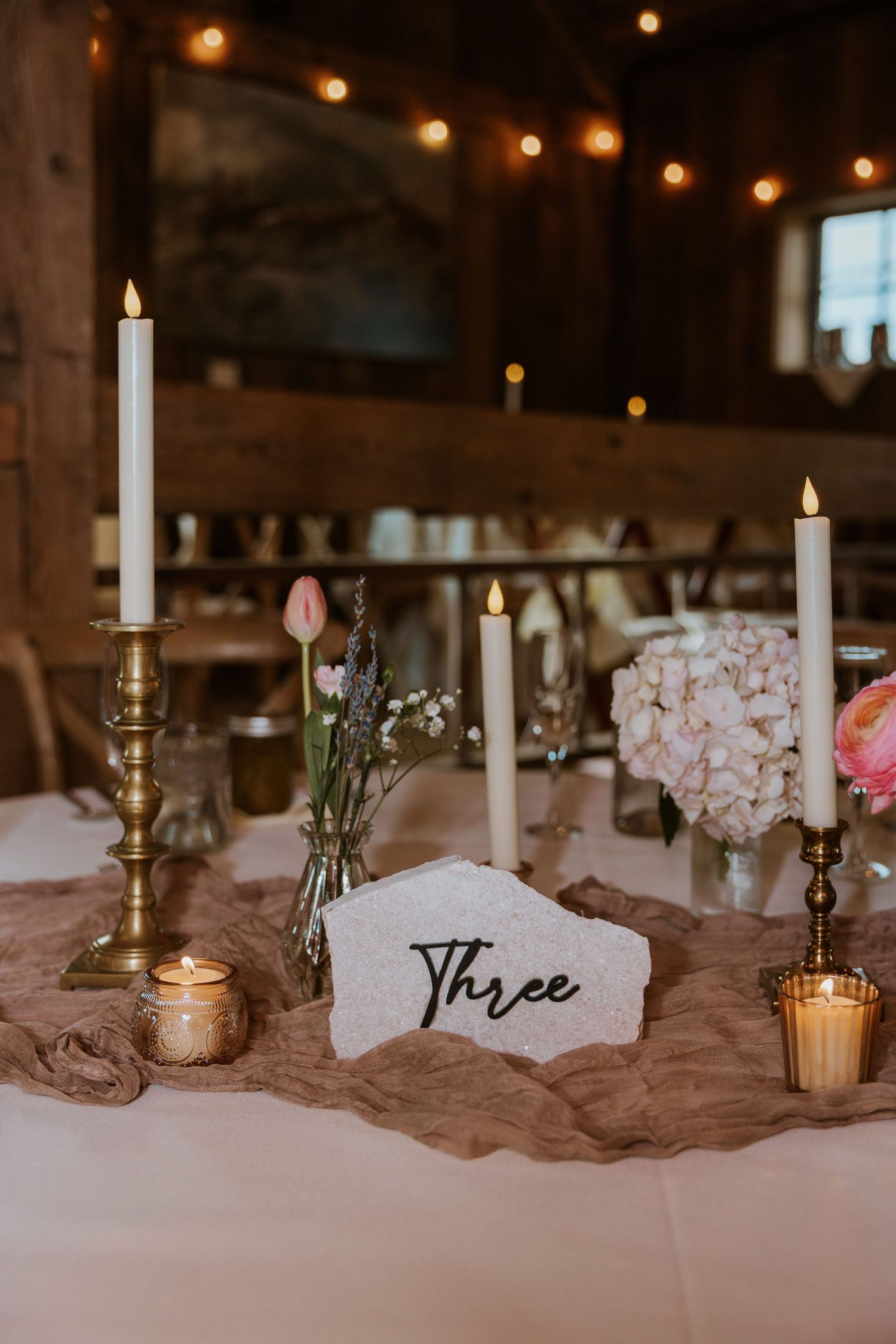 White lace sneakers rest on a wooden windowsill beside a delicate bouquet of dried pink and purple flowers.