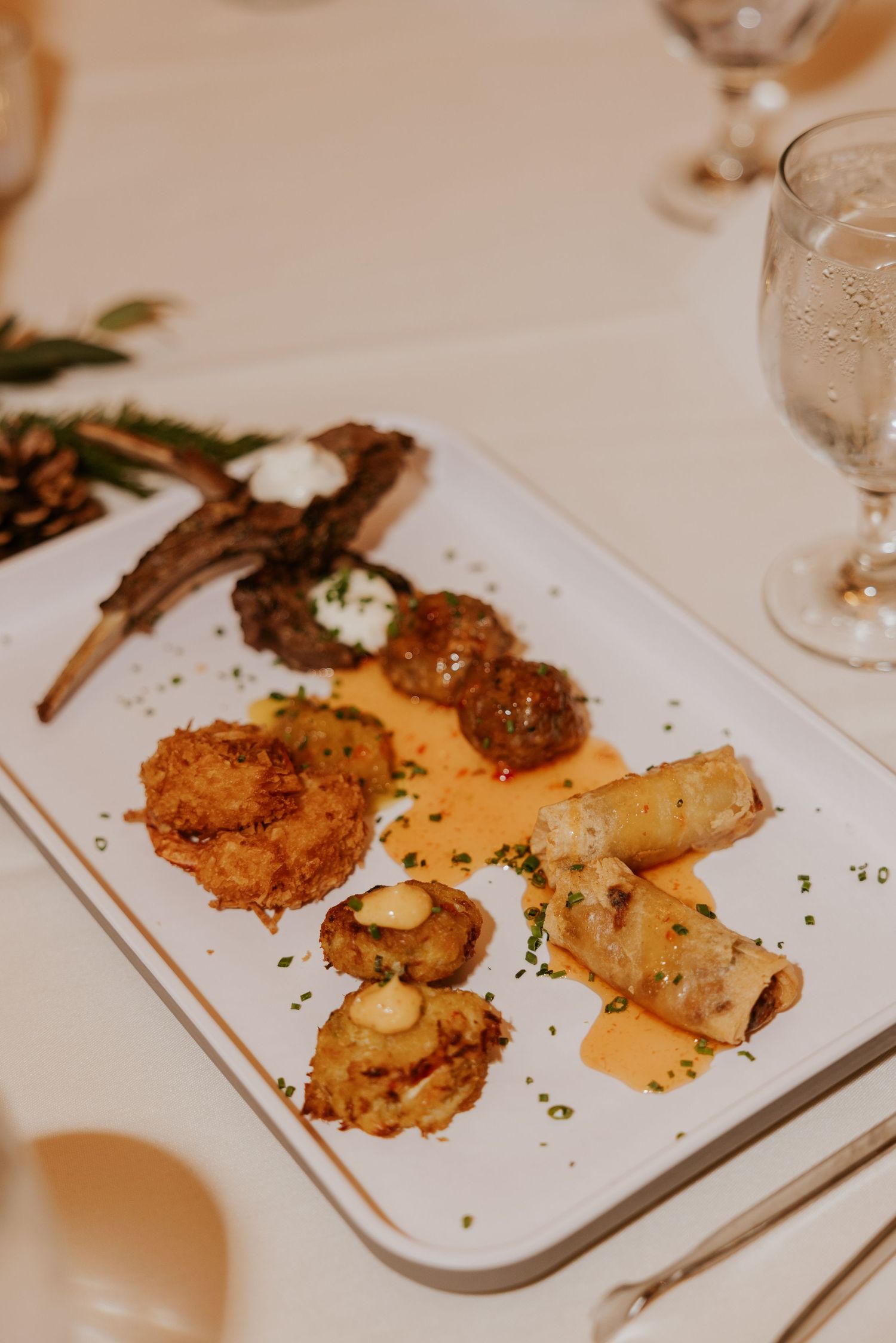 Elegant plated dinner dishes with golden-brown meat and garnishes served on white rectangular plates at an upscale restaurant.