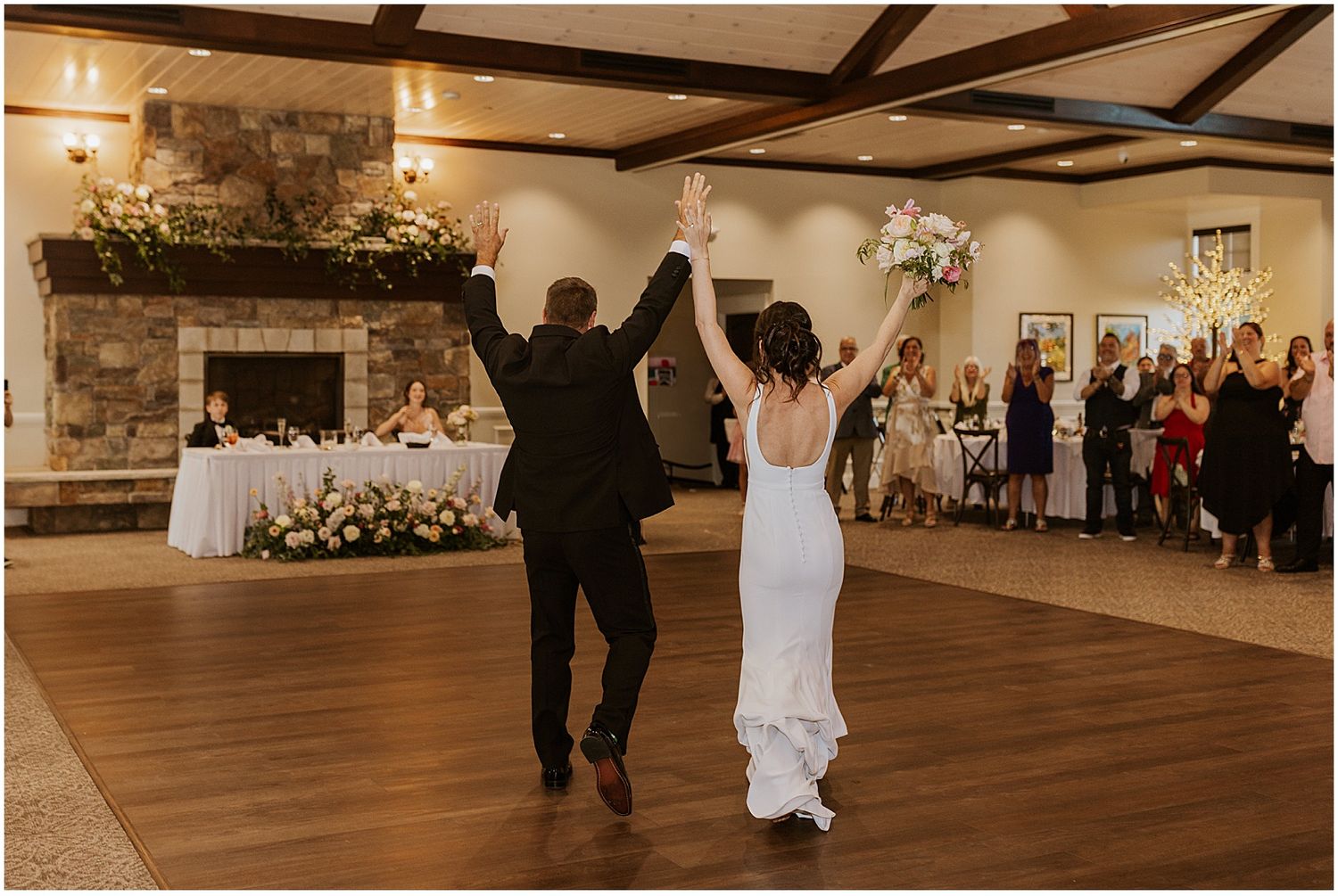 Spacious wedding reception hall with wooden beams and stone accent wall.