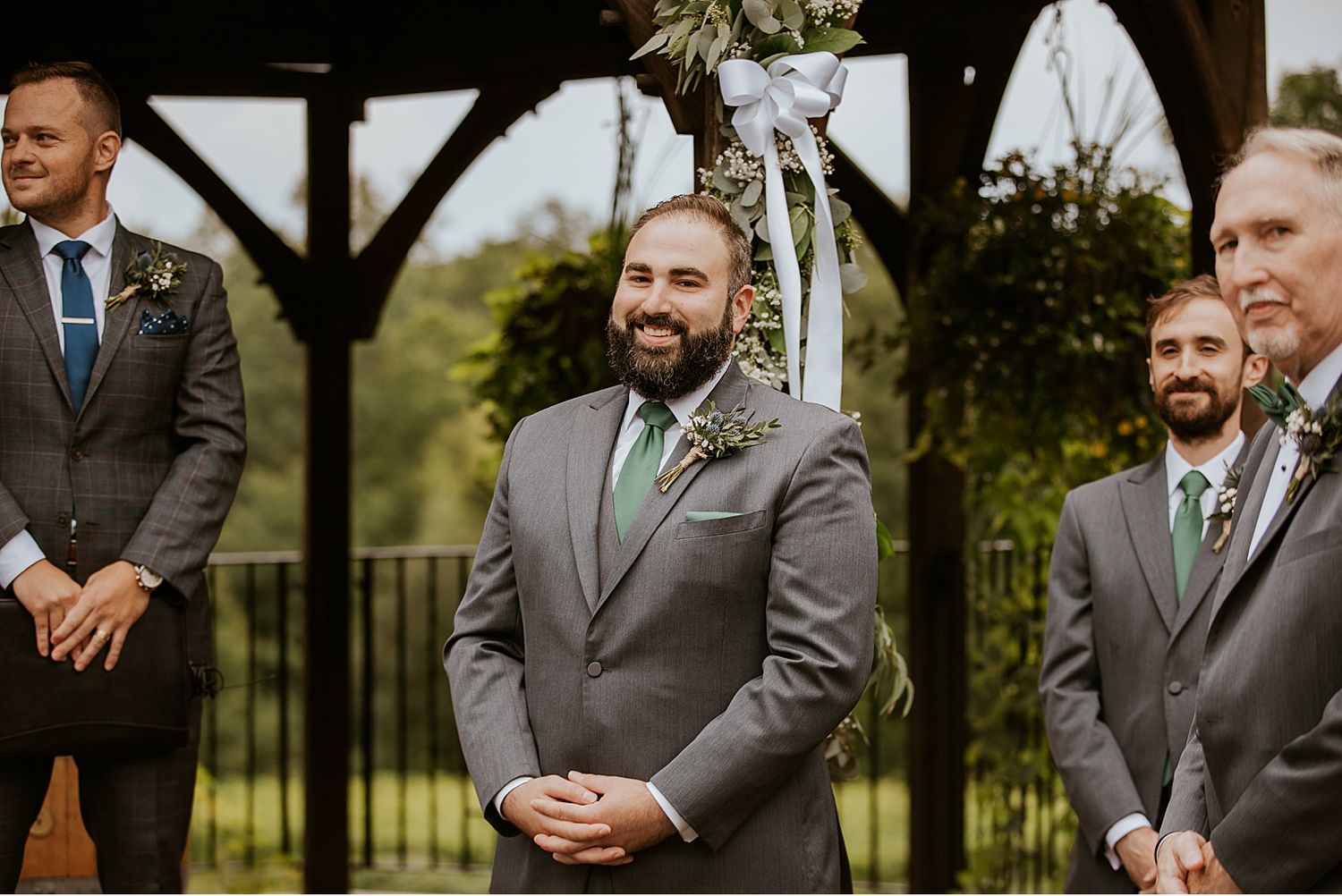Groomsmen in gray suits share laughs during outdoor wedding photos.