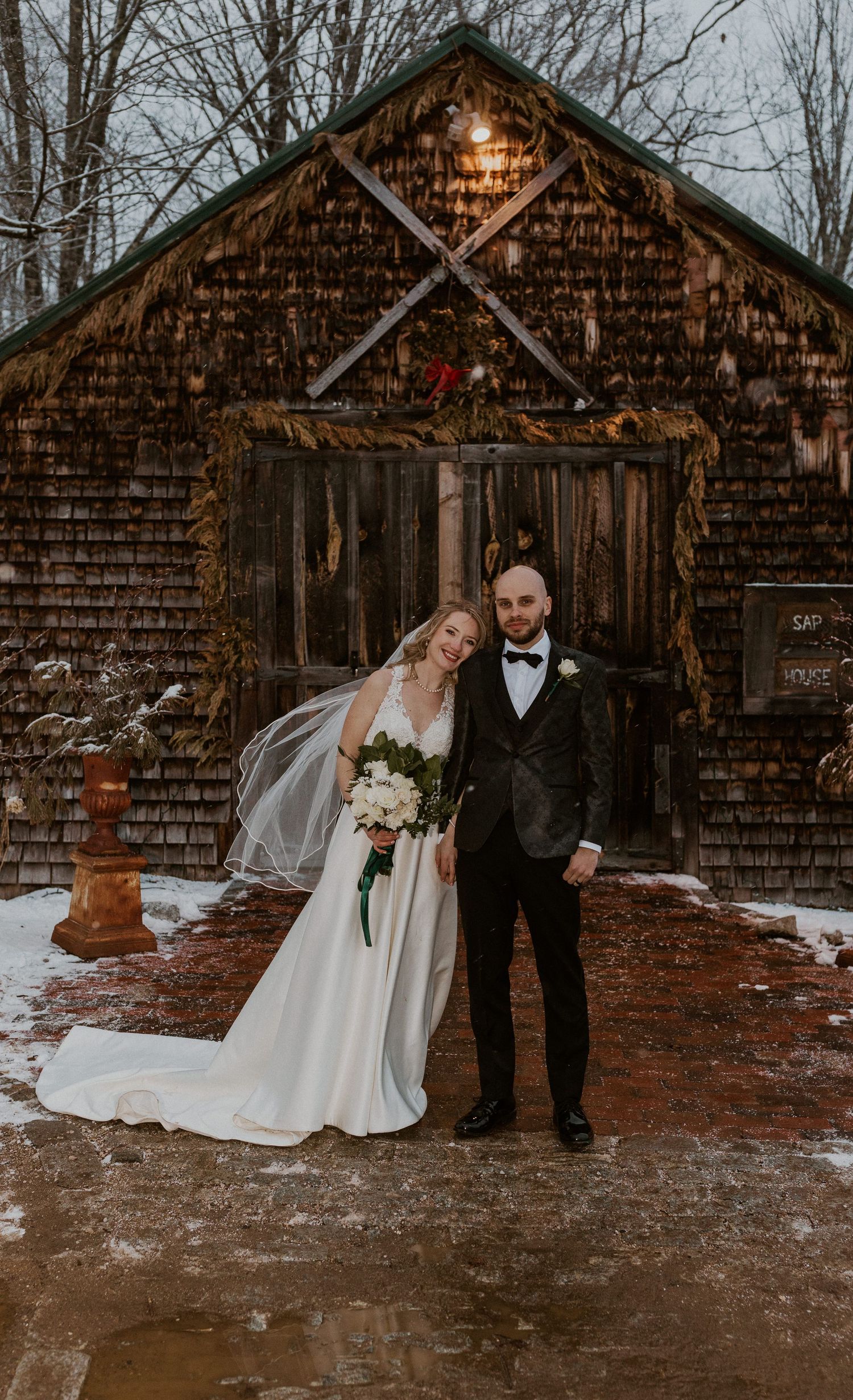 Deirdre and Brodie posing for portraits in front of the sap house at The Preserve in Tamworth New Hampshire.