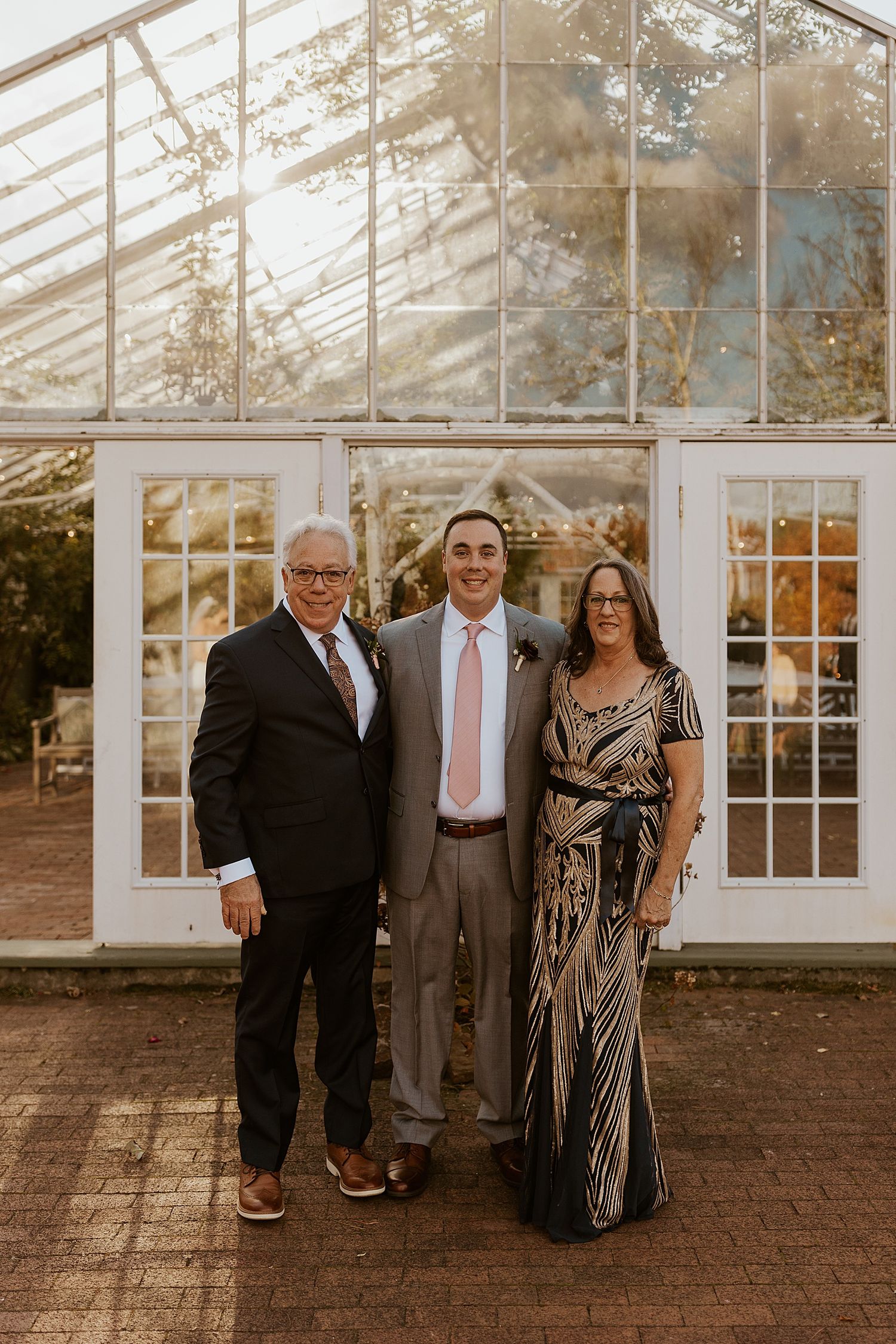 Groom taking portraits with his parents at his NH wedding