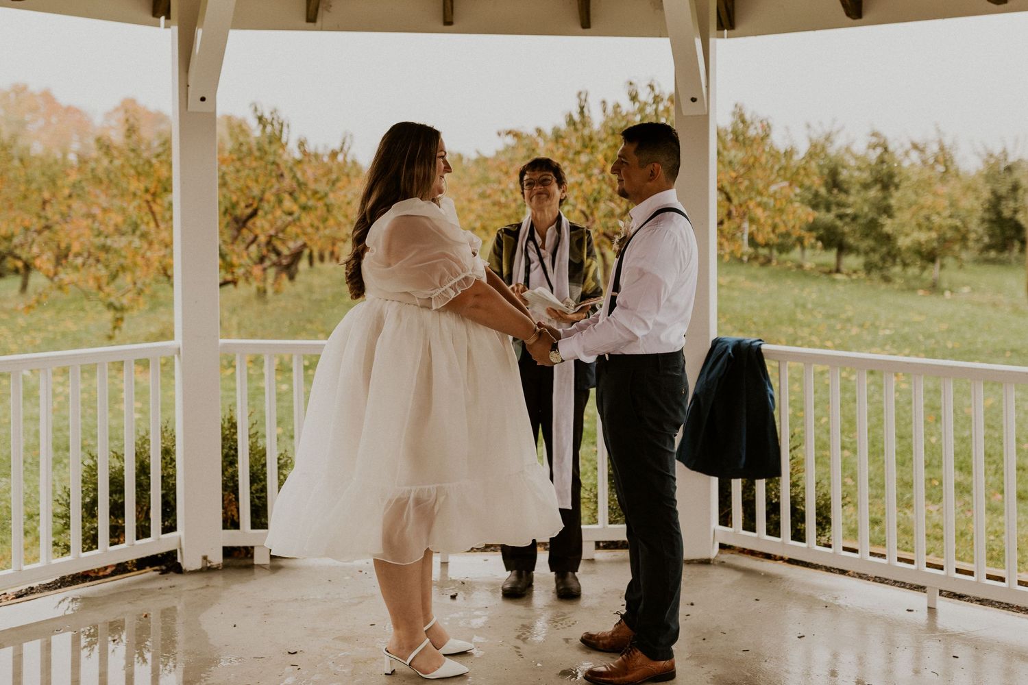Terise and Jose holding hands during their ceremony at Carter Hill Orchard in Concord New Hampshire.