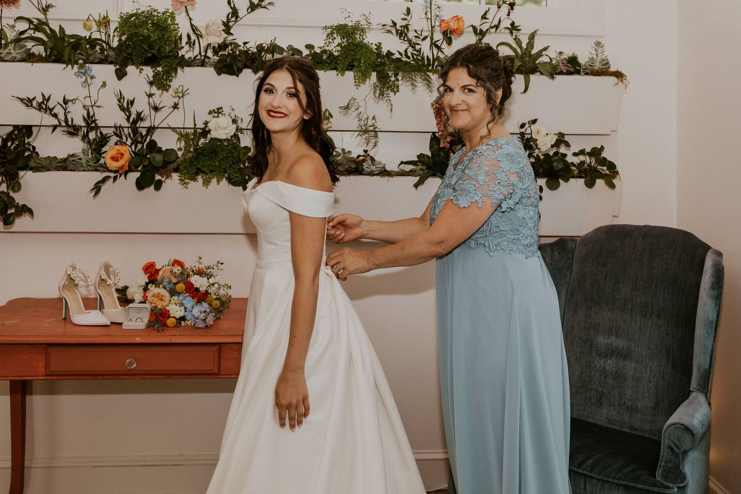 Wedding party gathered in an elegant room with vintage furniture and floral wall decorations.