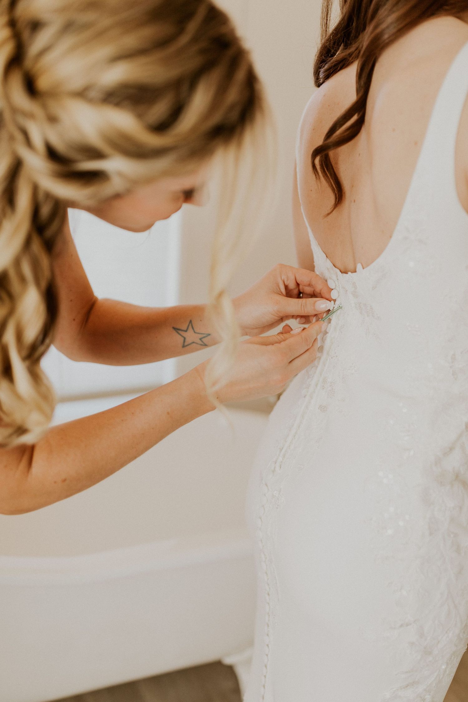 Briana's maid of honor buttoning her wedding gown while getting ready at the Woodstock Farmhouse in Woodstock NH