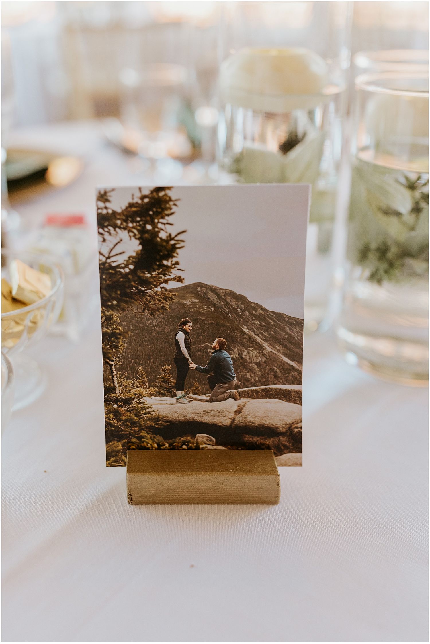 Engagement photo displayed on gold stand showing couple's mountain proposal moment.