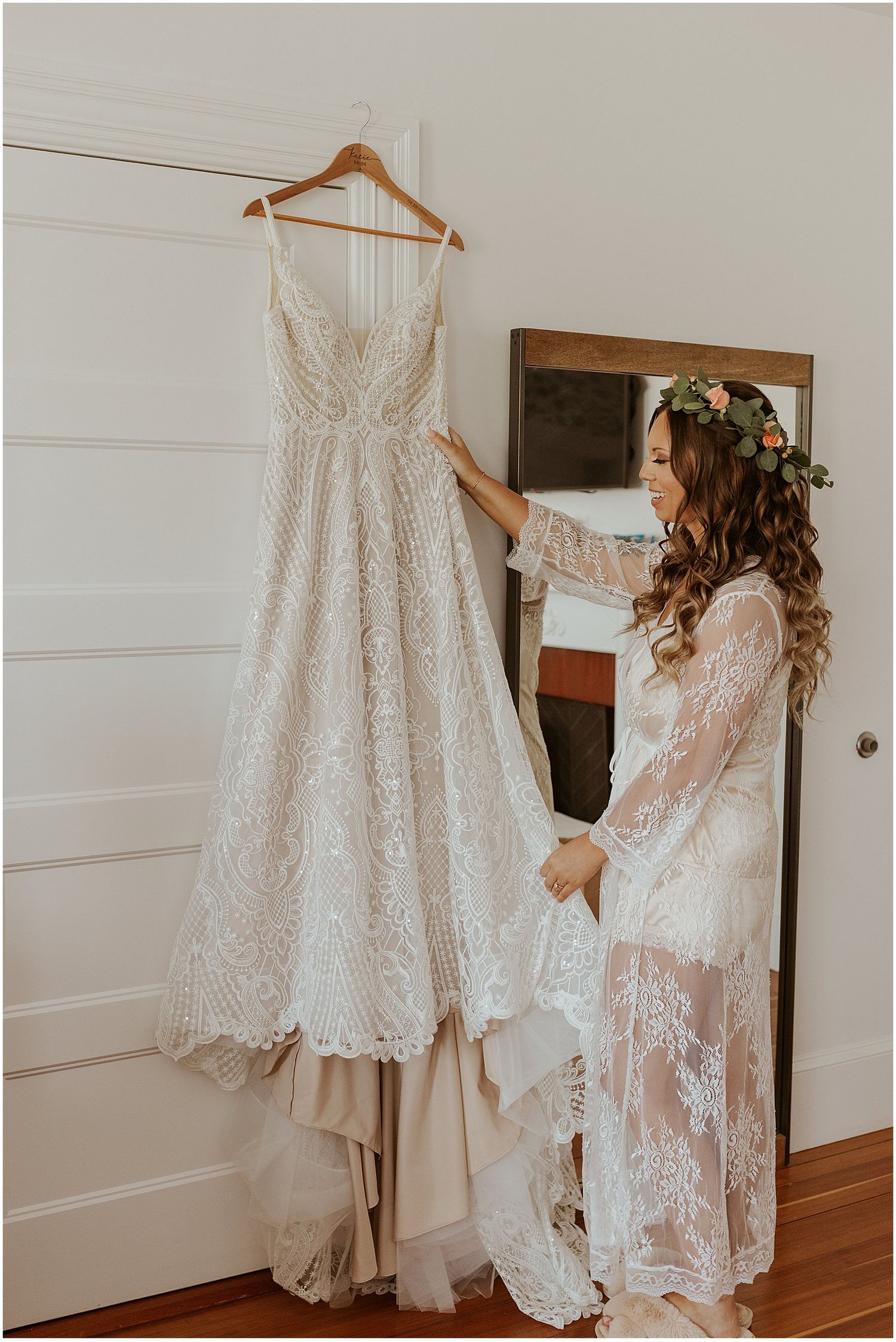 White lace wedding dress hanging on display in a bright, modern room.