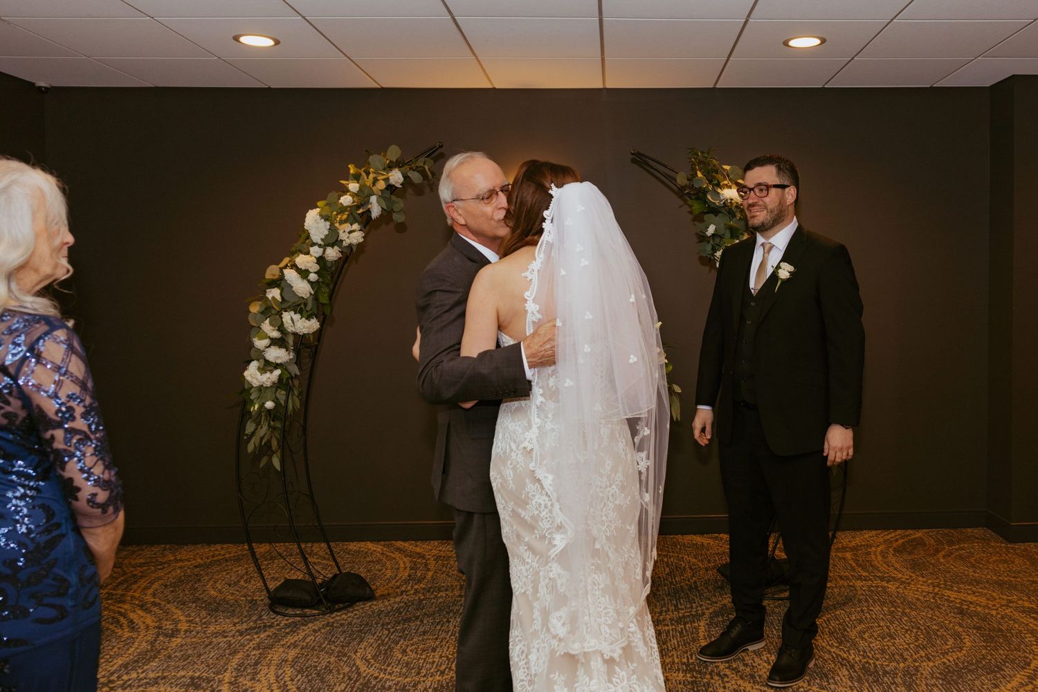 Wedding ceremony space decorated with white floral arrangements and elegant drapery.