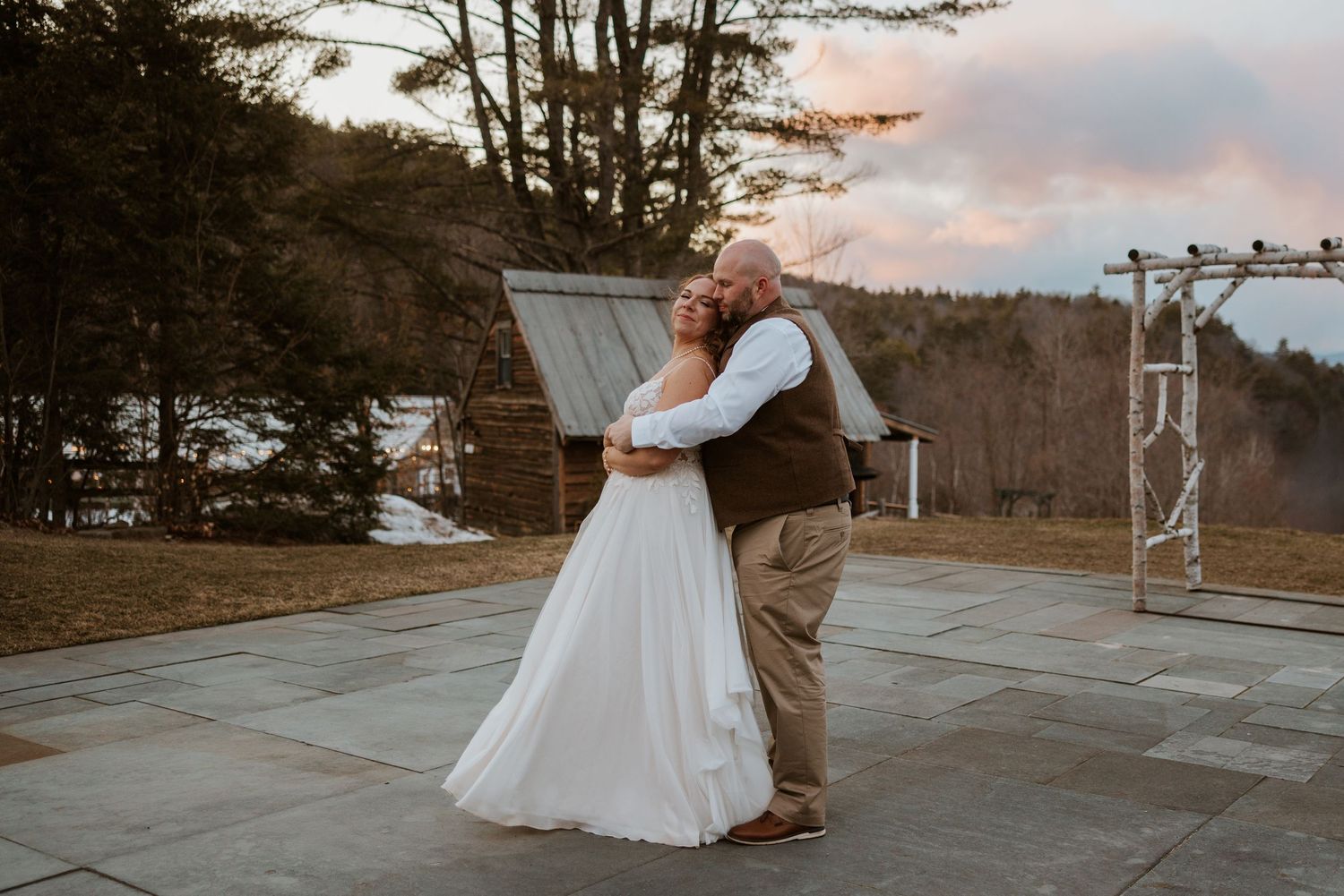 Couple dancing outdoors during sunset at their winter wedding celebration.