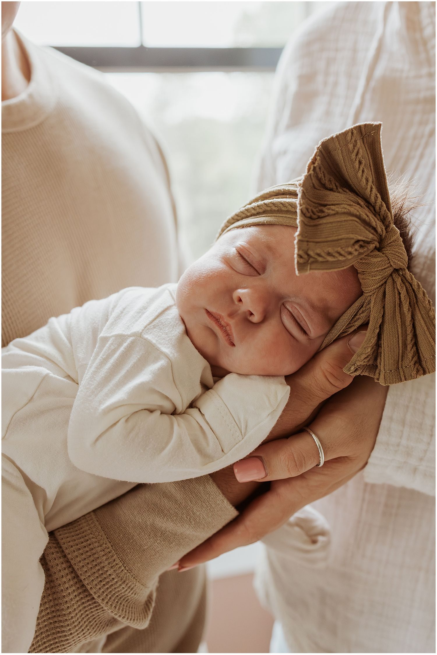 Newborn baby sleeping on her dad's arm while they take lifestyle newborn family photos at home
