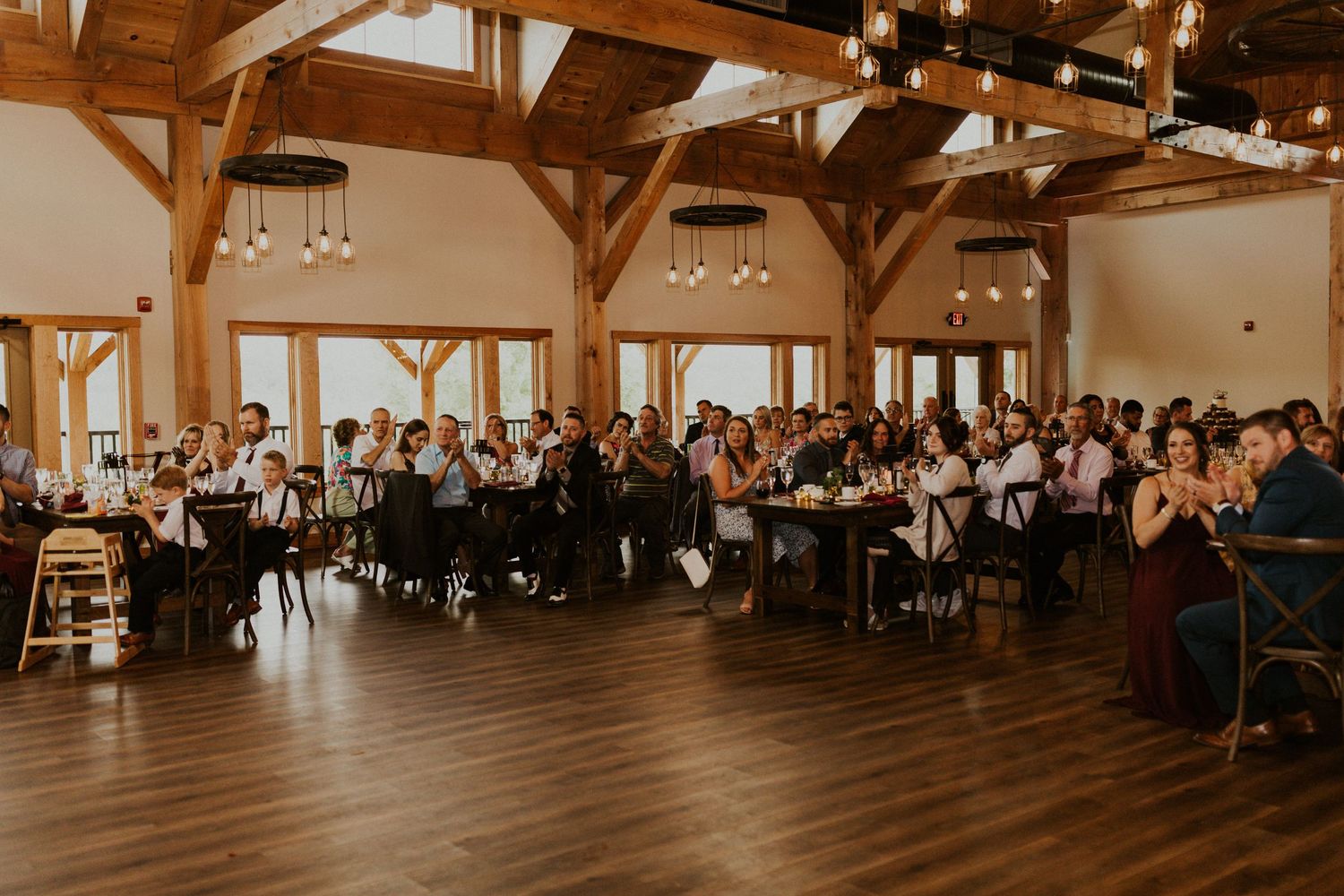 Spacious barn wedding venue with exposed beams and filled rows of guest tables.