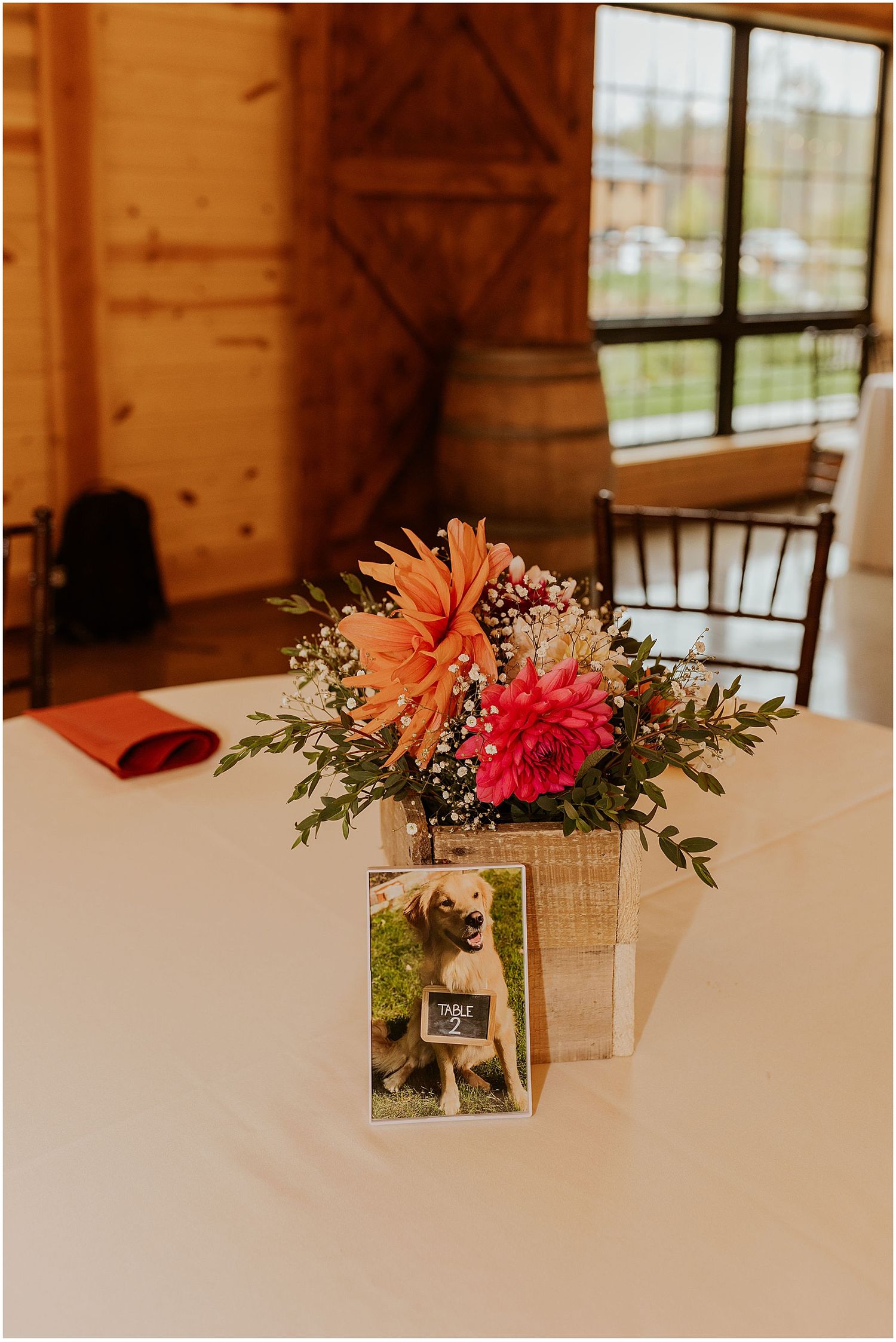 Wedding table decorations featuring framed photos and coral flower arrangements in wooden venue.