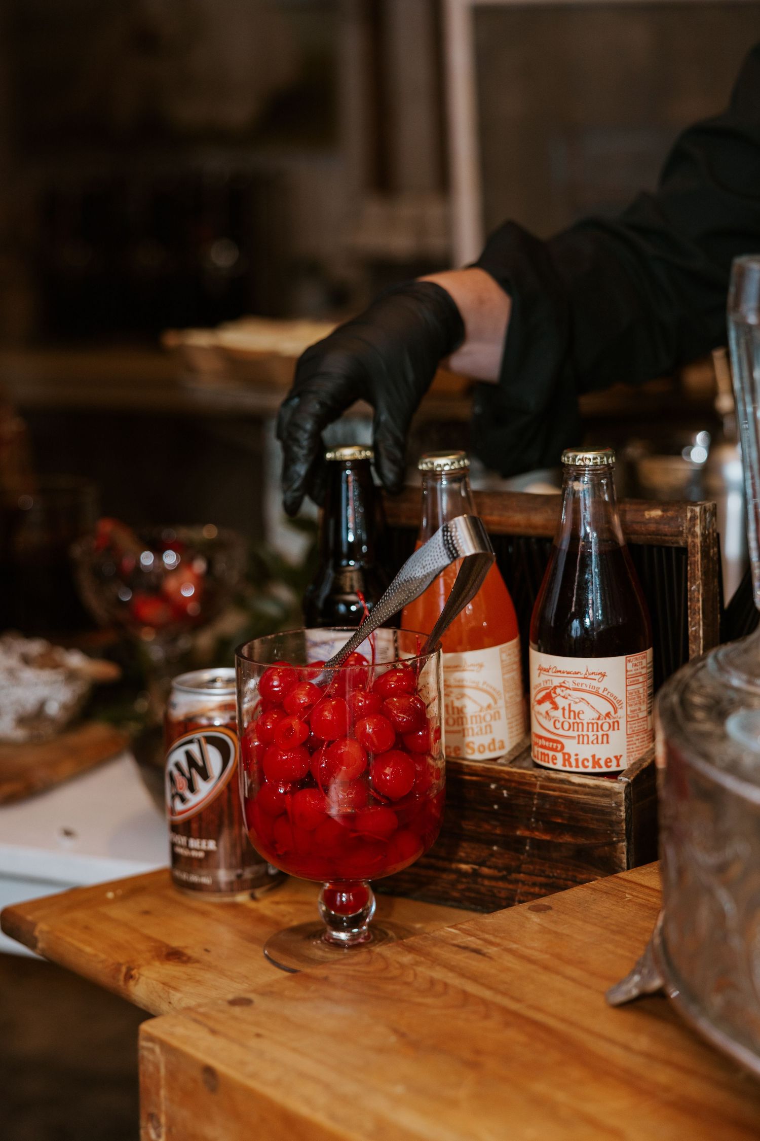 Vintage glass bottles and red cocktail cherries on wooden bar at wedding reception.