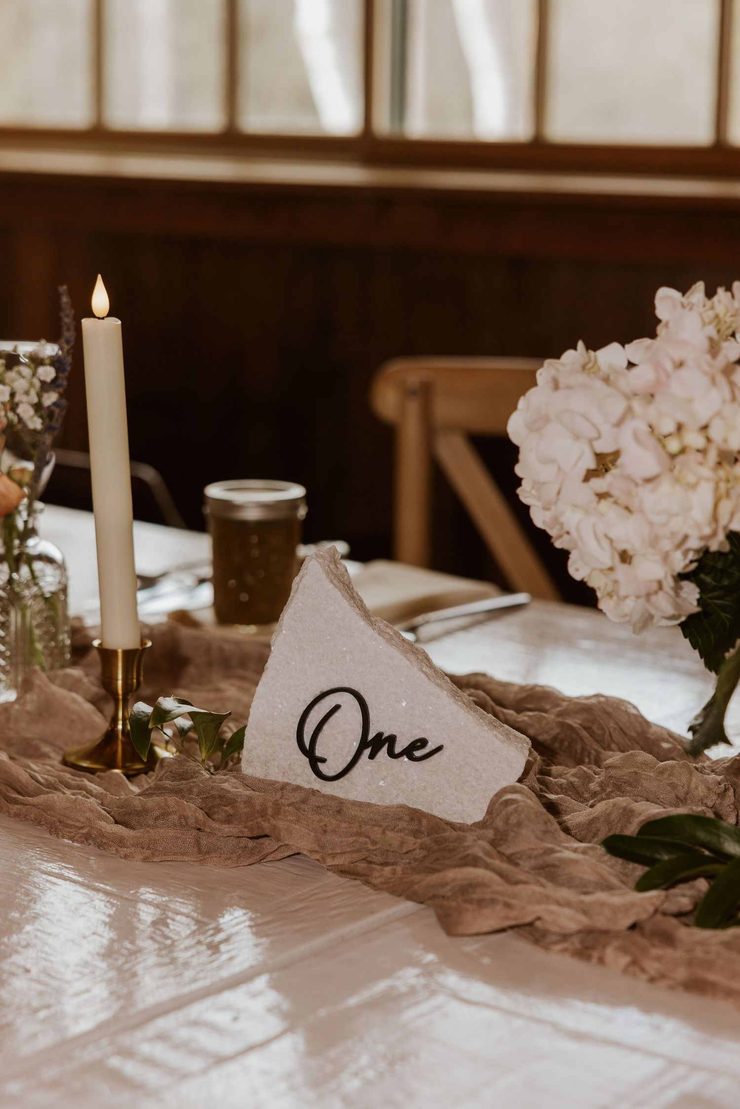 Elegant wedding table setting with white flowers, candles and flowing fabric table runner.