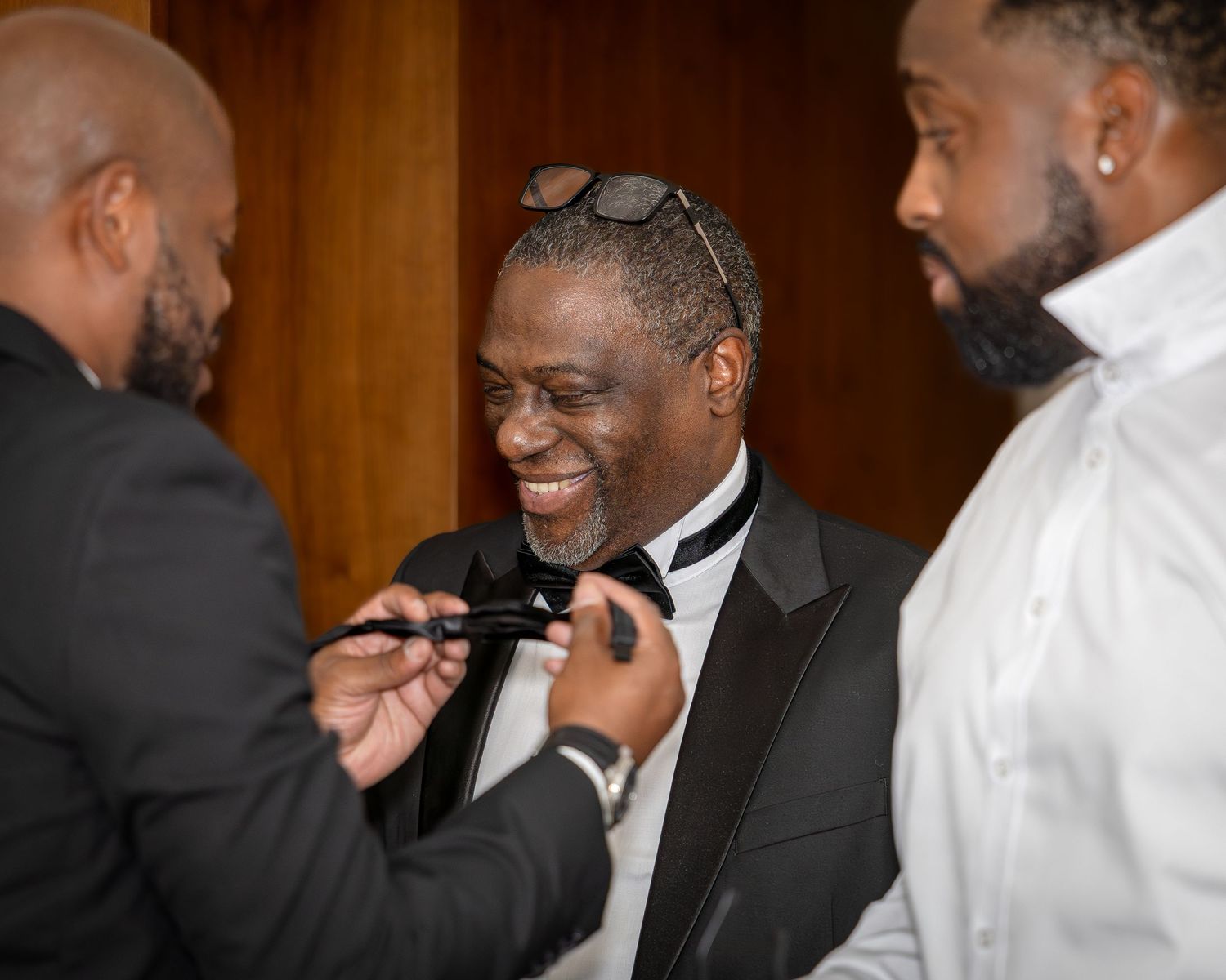 Wedding guests in formal attire sharing laughter during reception celebration.