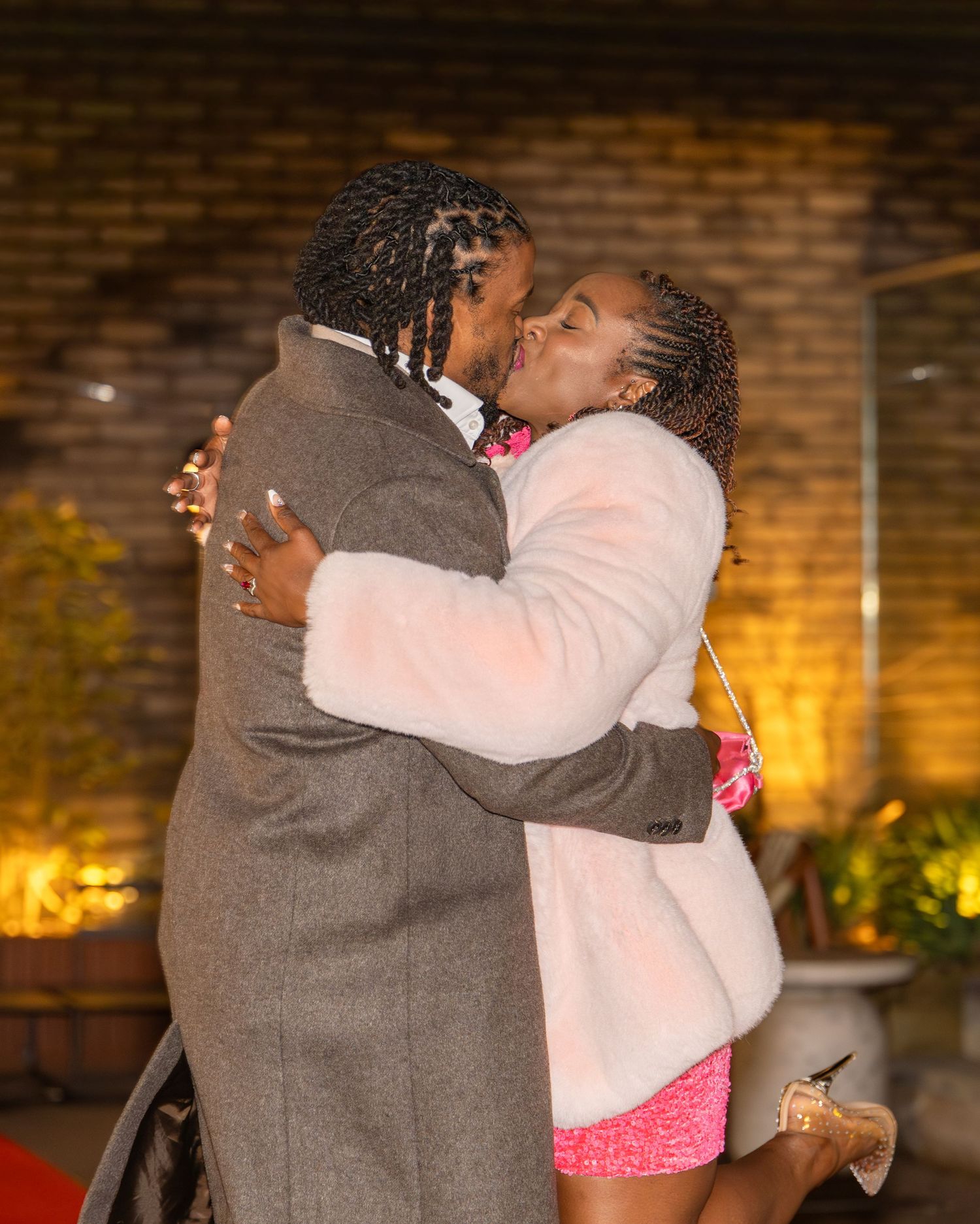 Couple embraces and kisses after a romantic marriage proposal outdoors at night.