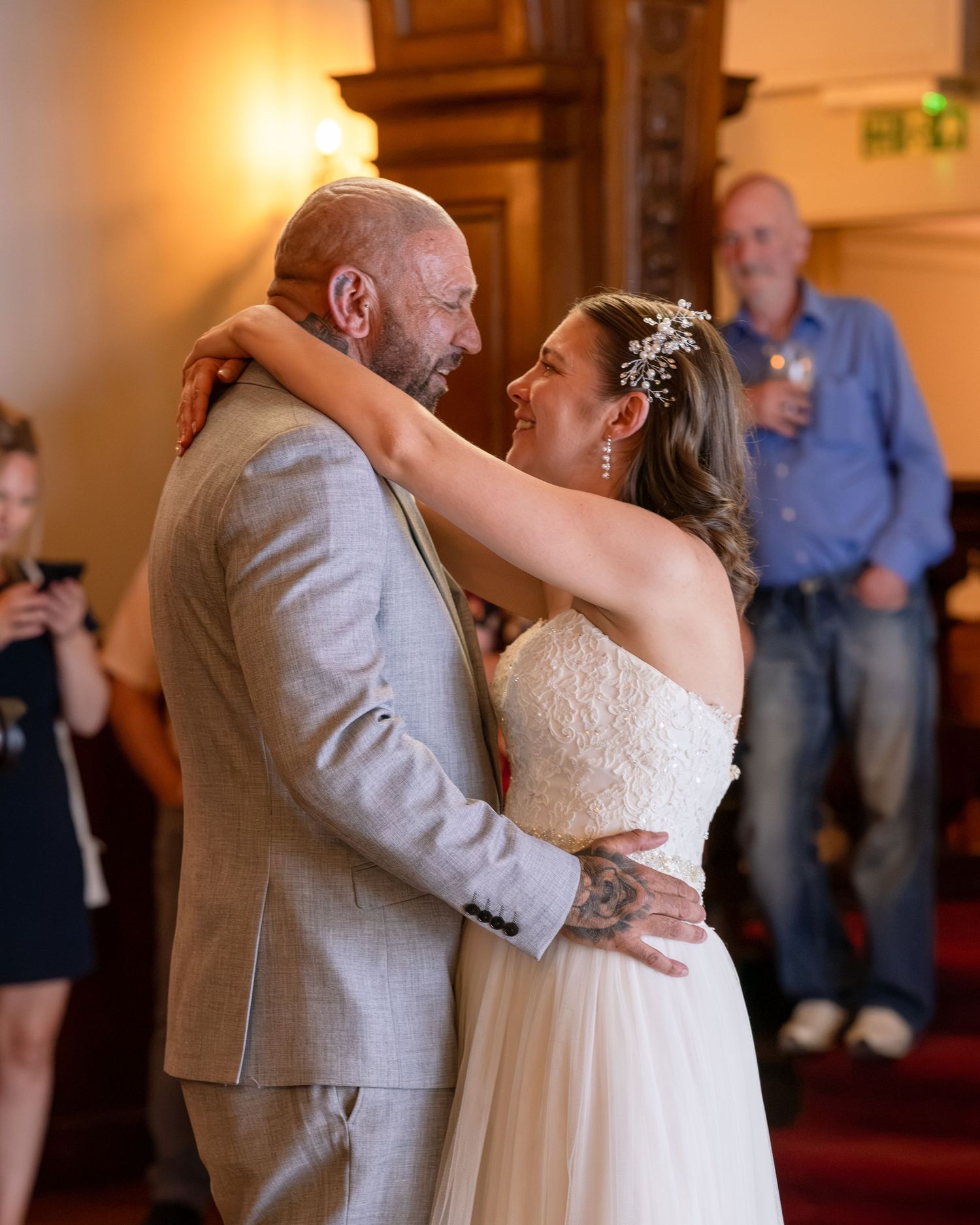 Bride and groom share their first dance at wedding reception, guests watching in elegant venue.