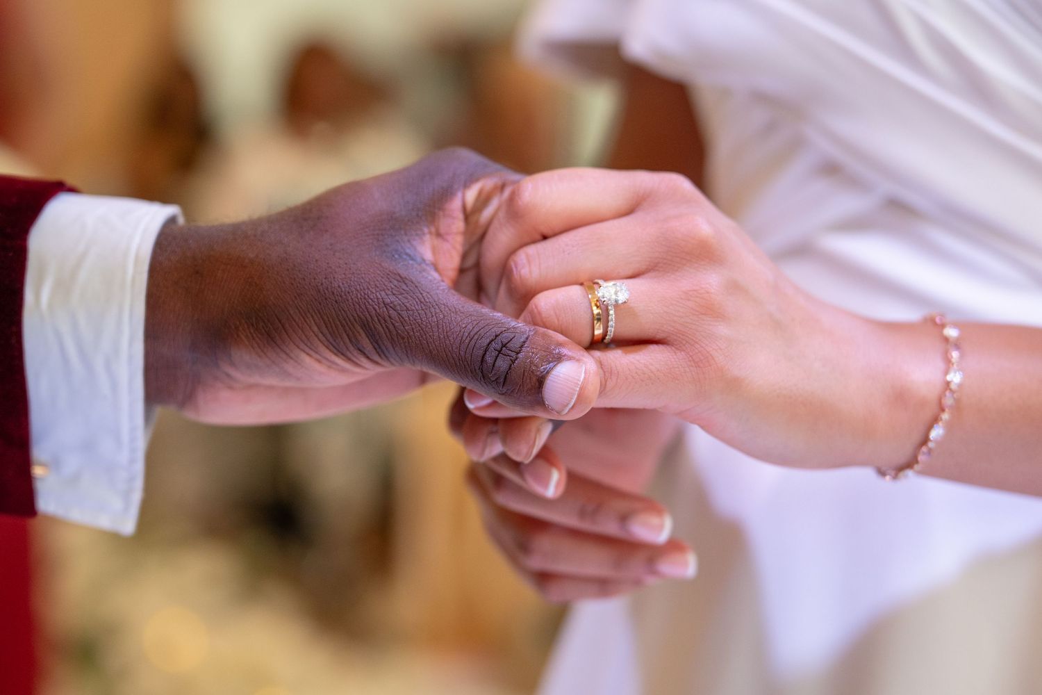 Close-up of interracial couple exchanging wedding rings during marriage ceremony, symbolizing love and unity.