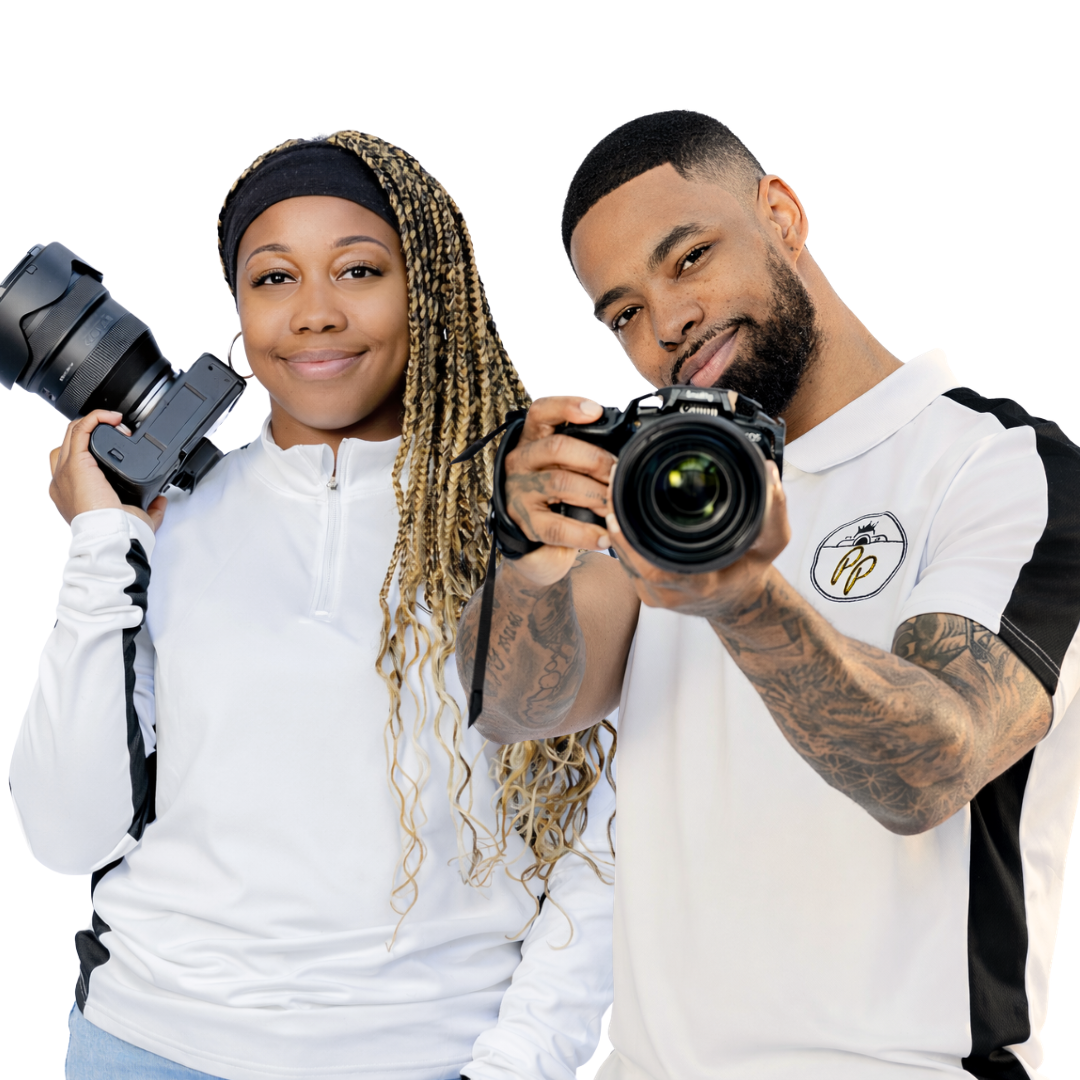 Two photographers in matching white shirts holding cameras posing against white background.