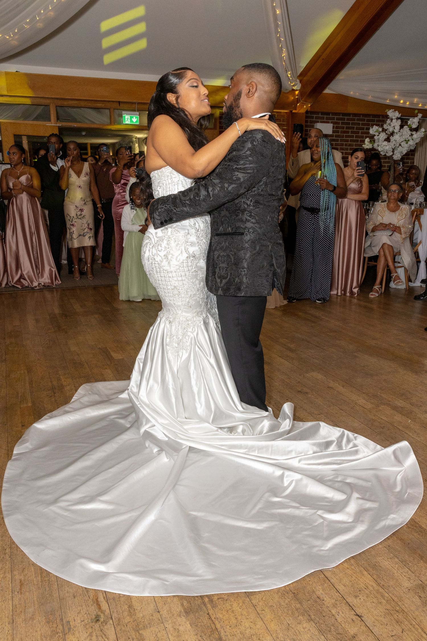 Bride in a stunning white mermaid gown shares first dance with groom in a patterned blazer.