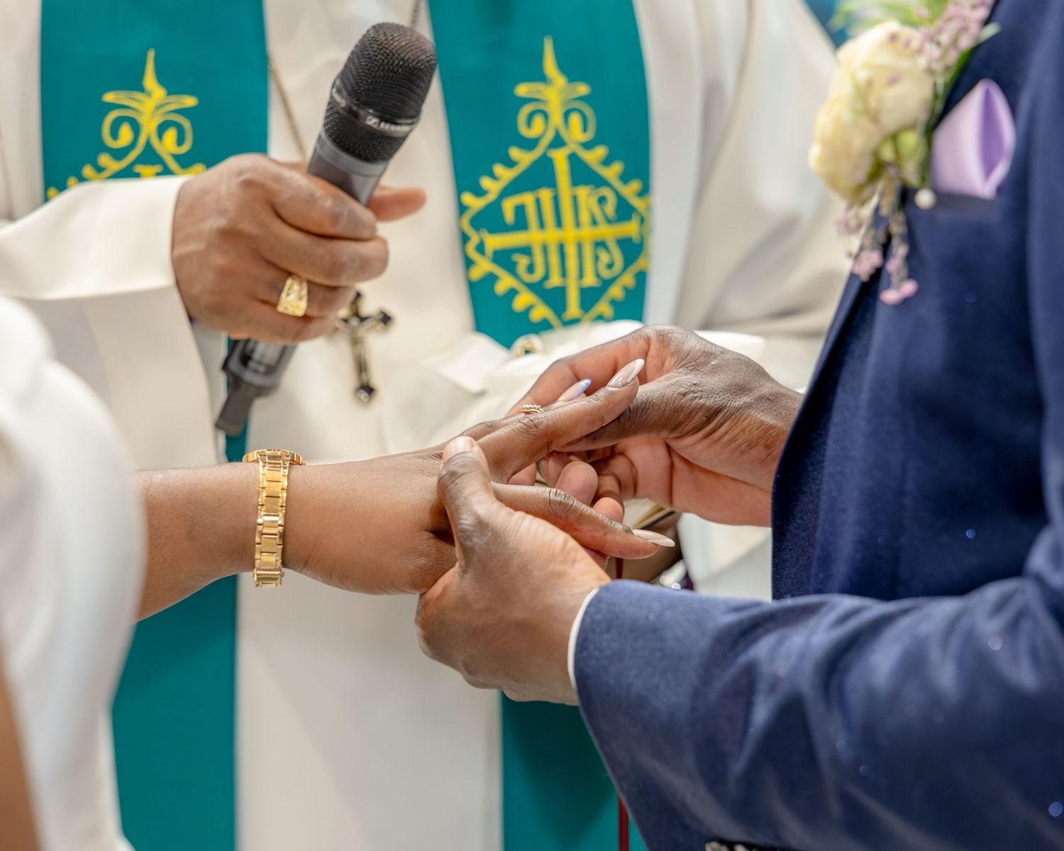 Priest officiates wedding ring exchange ceremony between bride and groom in church.