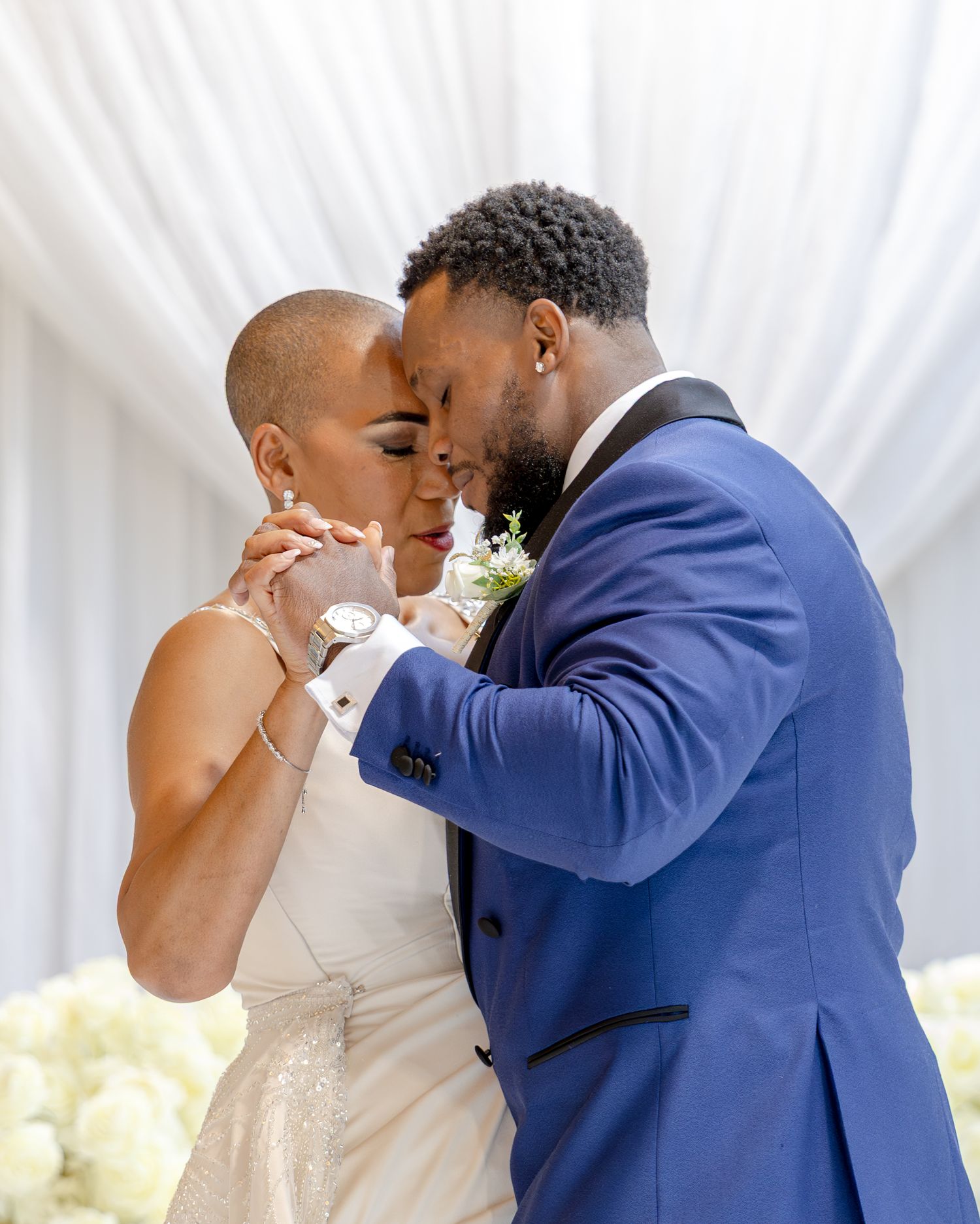 A bride and groom share an intimate moment, touching foreheads at their elegant wedding ceremony.
